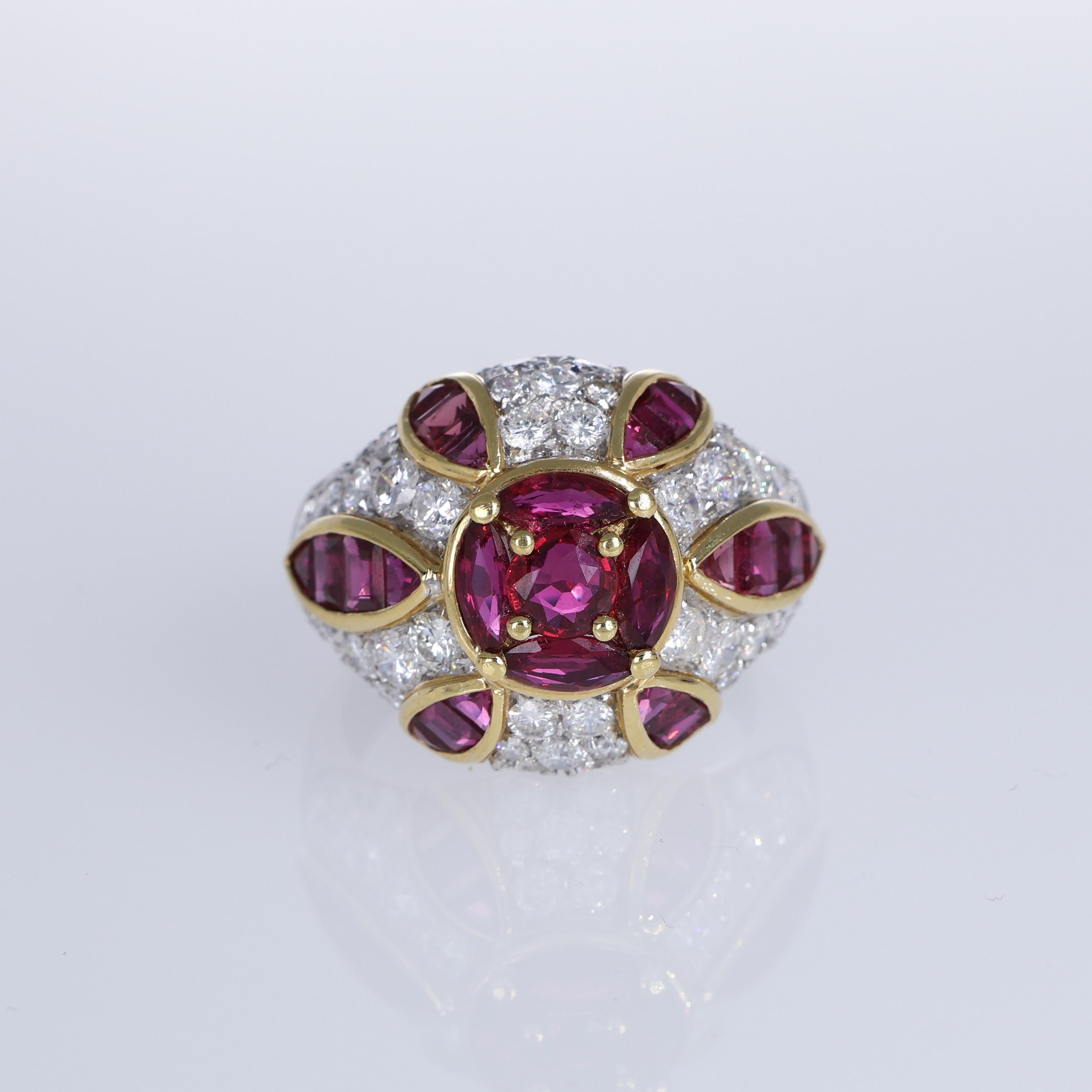 A stunning display of artistry, this 18K white and yellow gold ring features a central ruby encircled by petal-shaped rubies, creating a radiant floral motif. The musone-style band is adorned with pavé-set brilliant-cut diamonds, adding exceptional