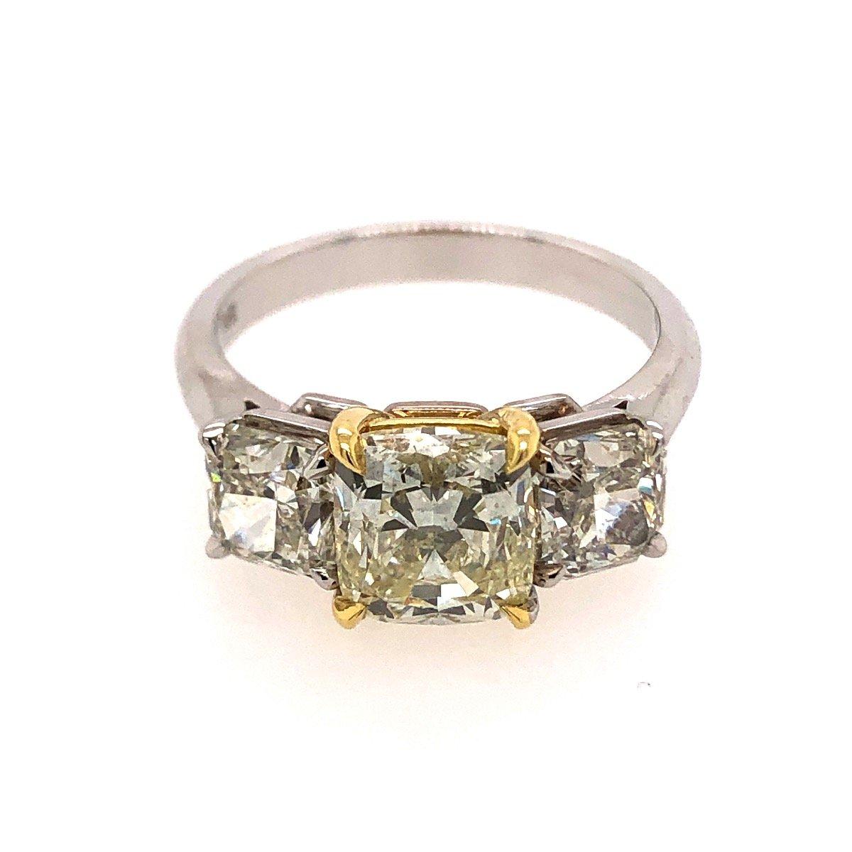 A beautiful three-stone diamond engagement ring set in 18 karat yellow and white gold. The ring prominently features three graduating Cushion cut diamonds in a white gold. Center stone is set with yellow gold. Center stone: 2.20cts. Sides stone: