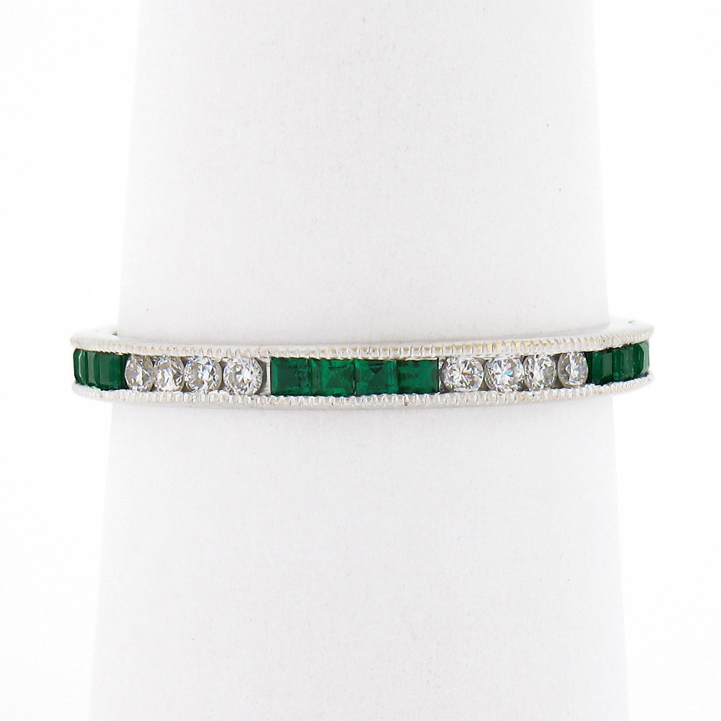 This marvelous emerald and diamond eternity band ring is crafted in solid 18k white gold and features a well made channel setting which is delicately milgrain etched throughout both sides, and securely holds the stunning stones entirely around the