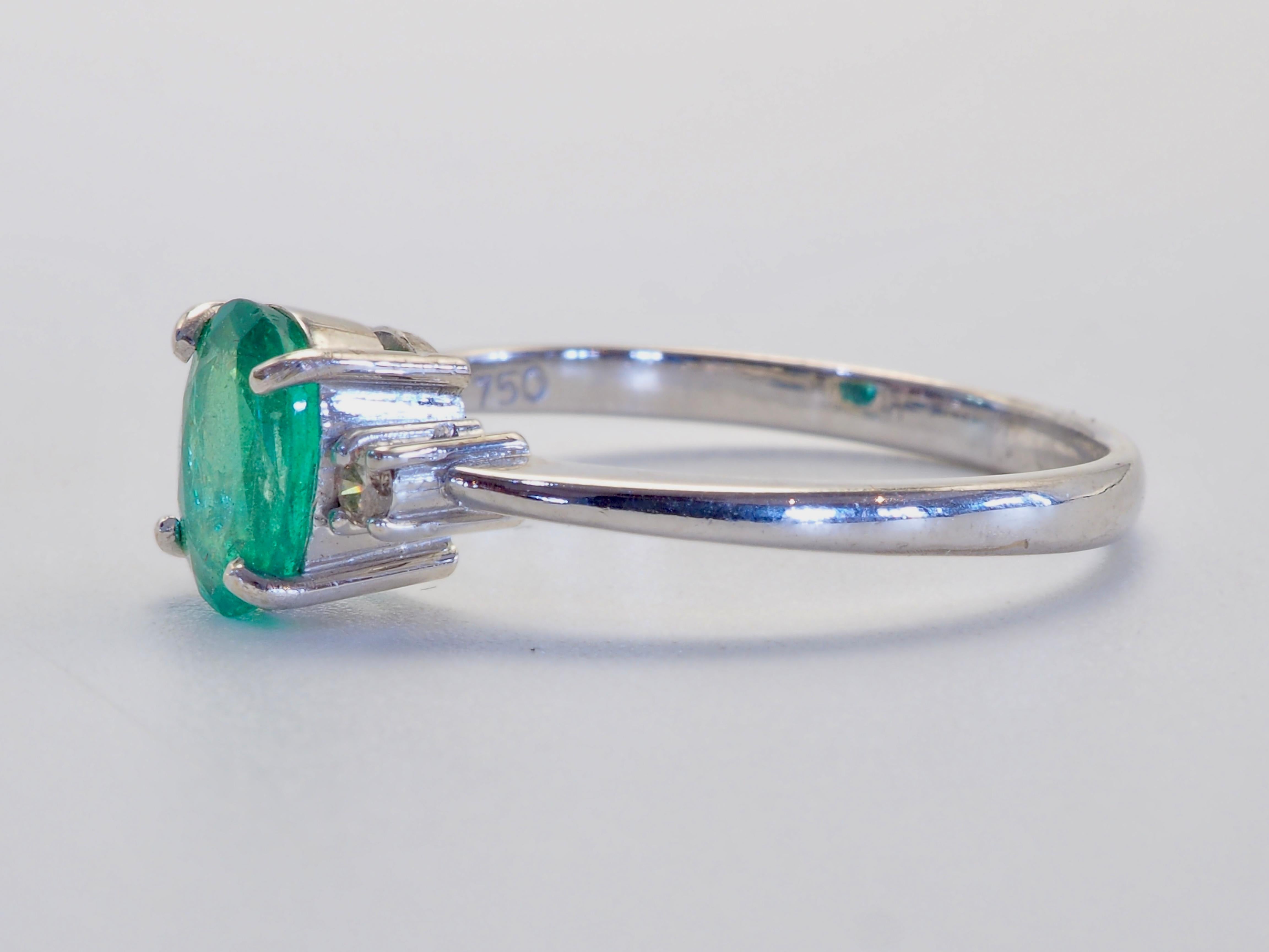 Classic and timeless Italian design three stone ring with a petit bright green oval emerald and 2 brilliantly decent grade diamonds. Emerald has typical inclusion visible through naked eye. For those who have a soft spot for emeralds and white