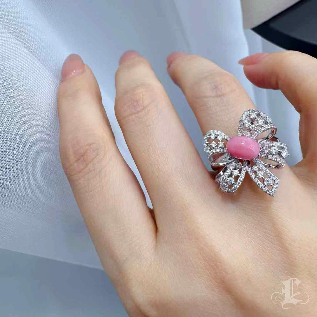 A graceful tribute to movement and femininity, this sculptural ring features a 1.74-carat flamingo pink conch pearl nestled at the center of a diamond-studded bow. Crafted in 18K gold and adorned with 0.75 carats of natural diamonds, the design