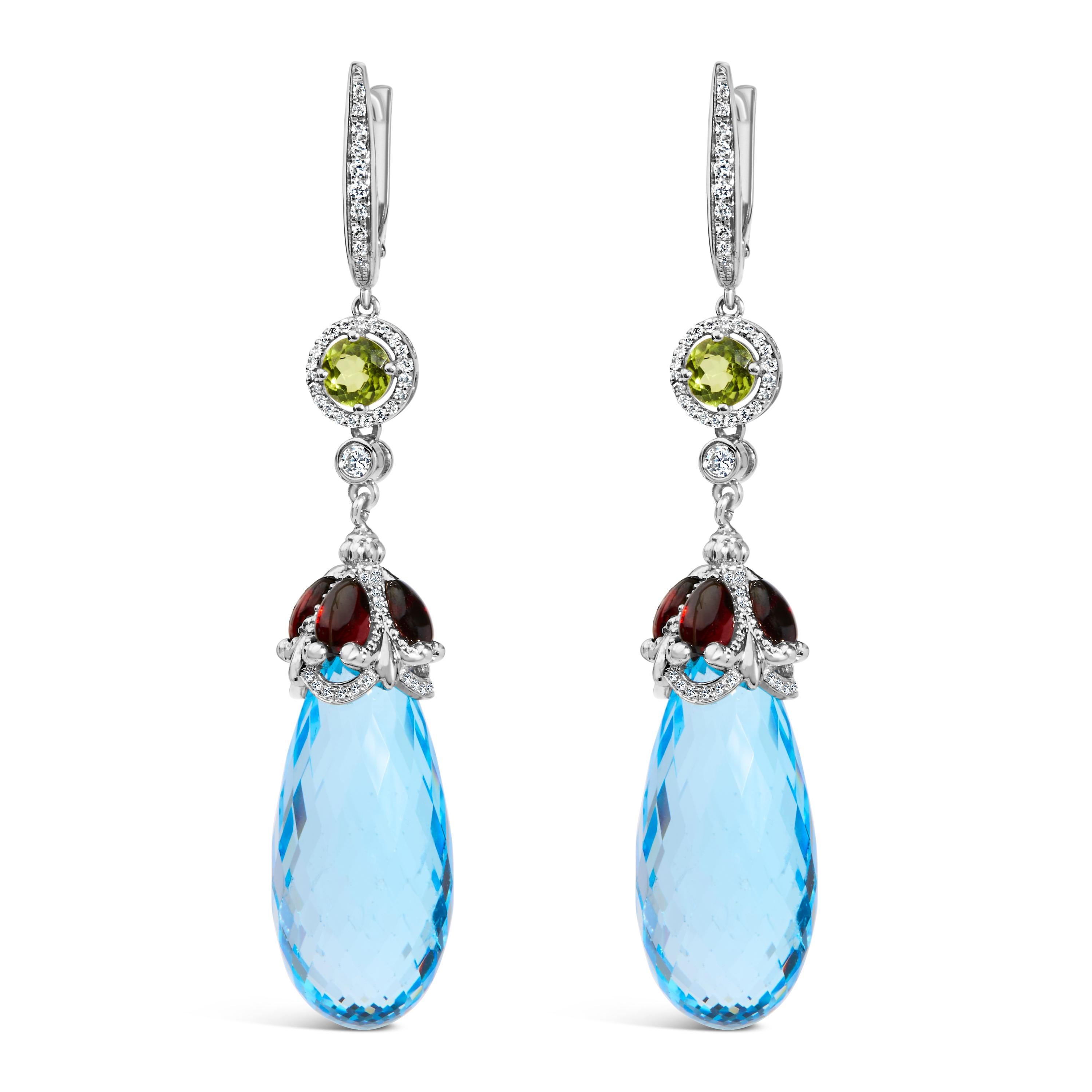 Immerse yourself in the opulence of these exquisite 18K white gold earrings, where the brilliance of natural diamonds meets the mystical allure of color-treated blue topaz and red garnet. Each earring gracefully dangles at a length of 2 4/5 inches,