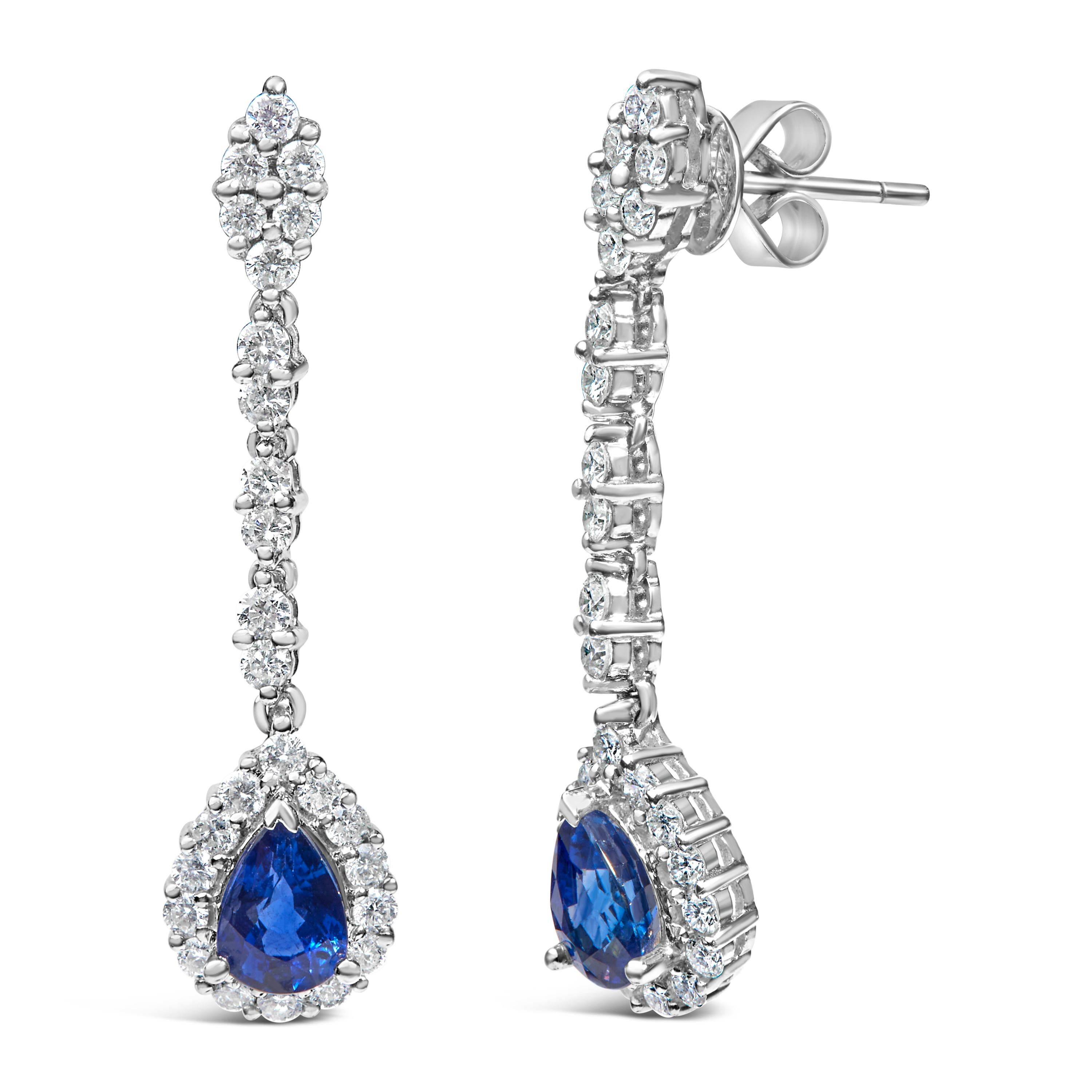 Imbued with an ethereal charm, these magnificent earrings, crafted from 18K white gold enhanced with a shimmering rhodium plate, proclaim unabashed elegance. At the heart of each earring sits a captivating, pear-shaped blue sapphire, naturally