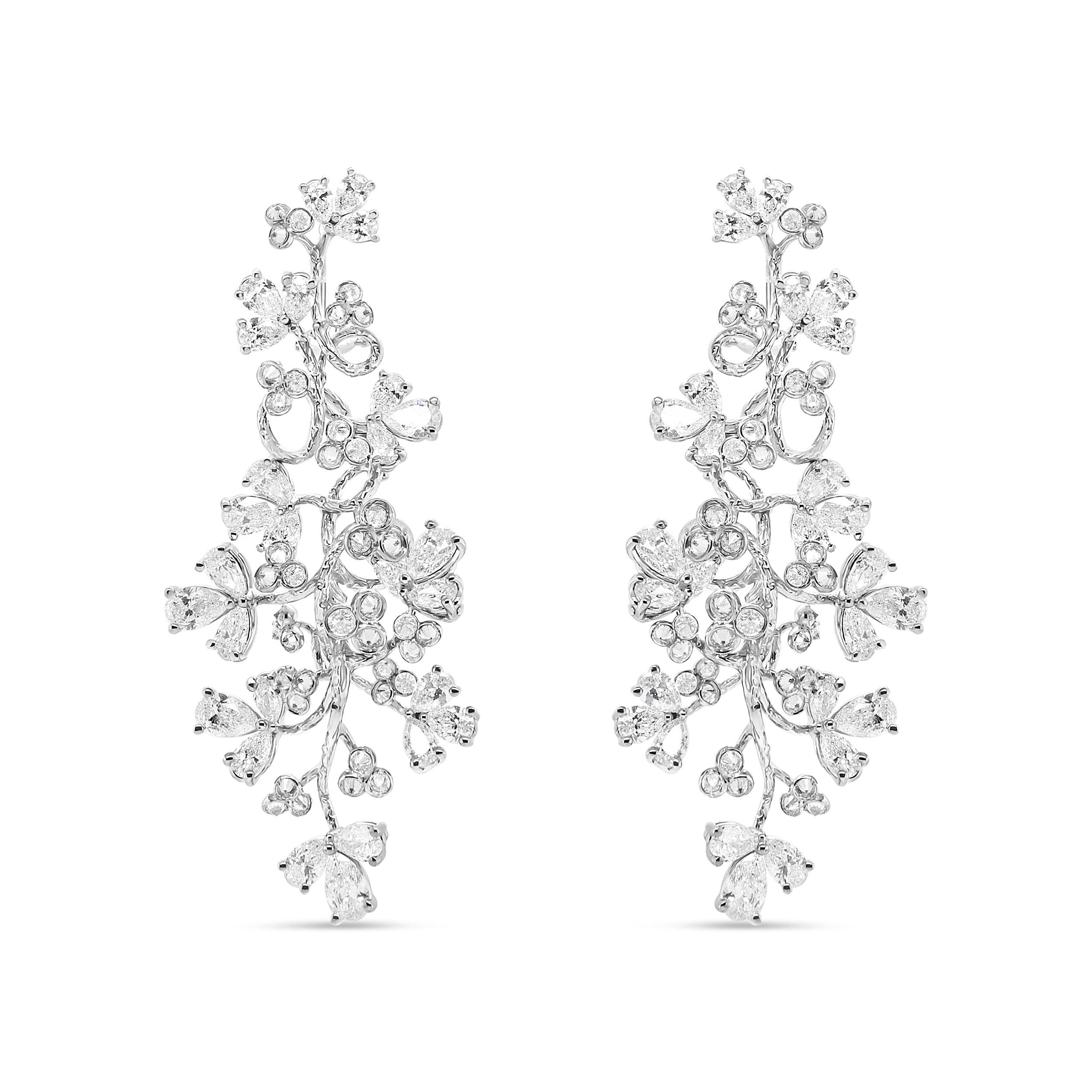 Alive with the wonder and magic of diamonds inspired by nature, this pair of 18k white gold floral motif earrings is an elegant stunner. The intricate design of these earrings beholds blooms of pear-shaped diamonds in 3 prong settings met with round