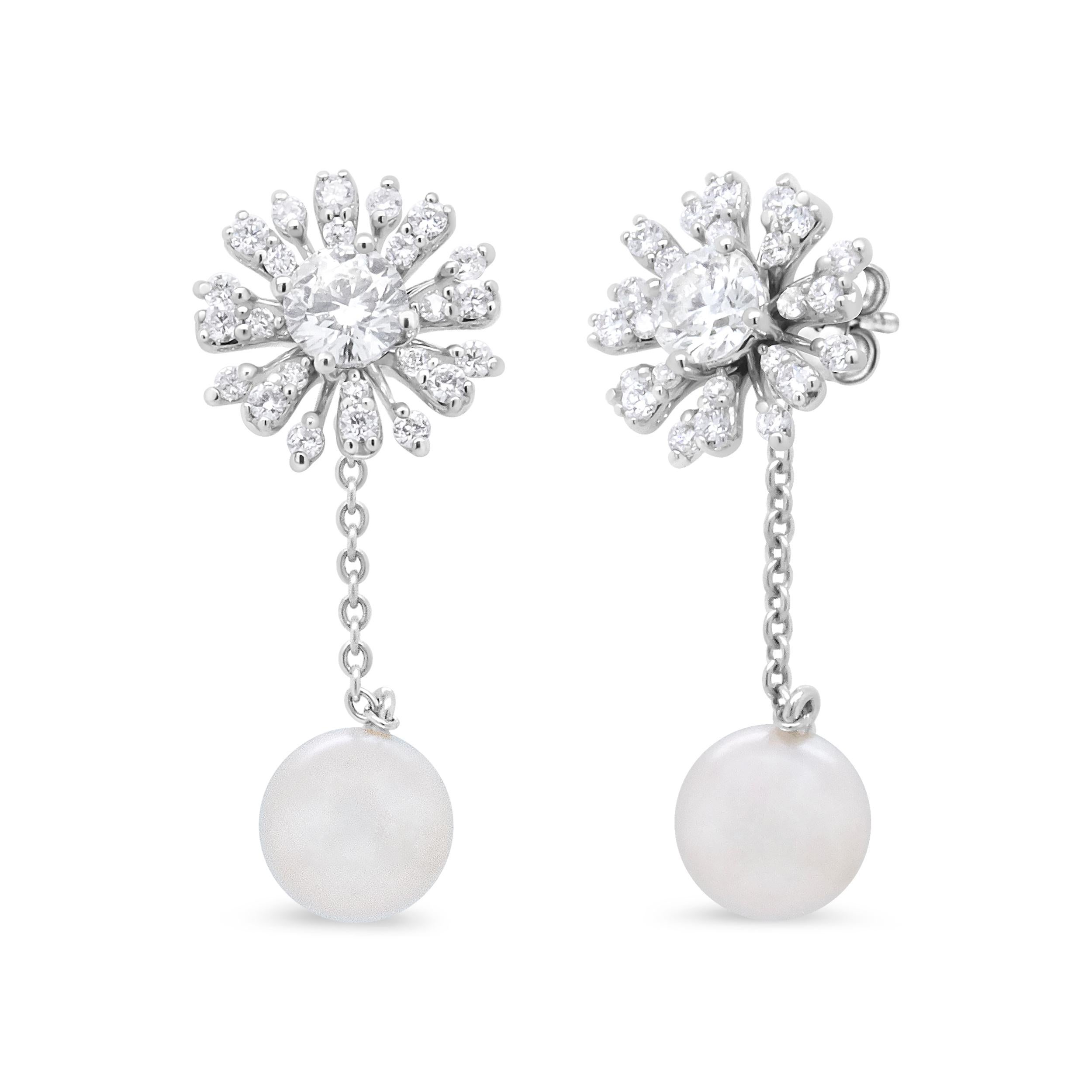 Exuding elegance from top to bottom, these 18k white gold drop earrings feature an enchanting 3/4 inch dangle length emblazoned with diamonds and freshwater pearls. The upper dangle is a brilliant flower silhouette prong-set with the astounding