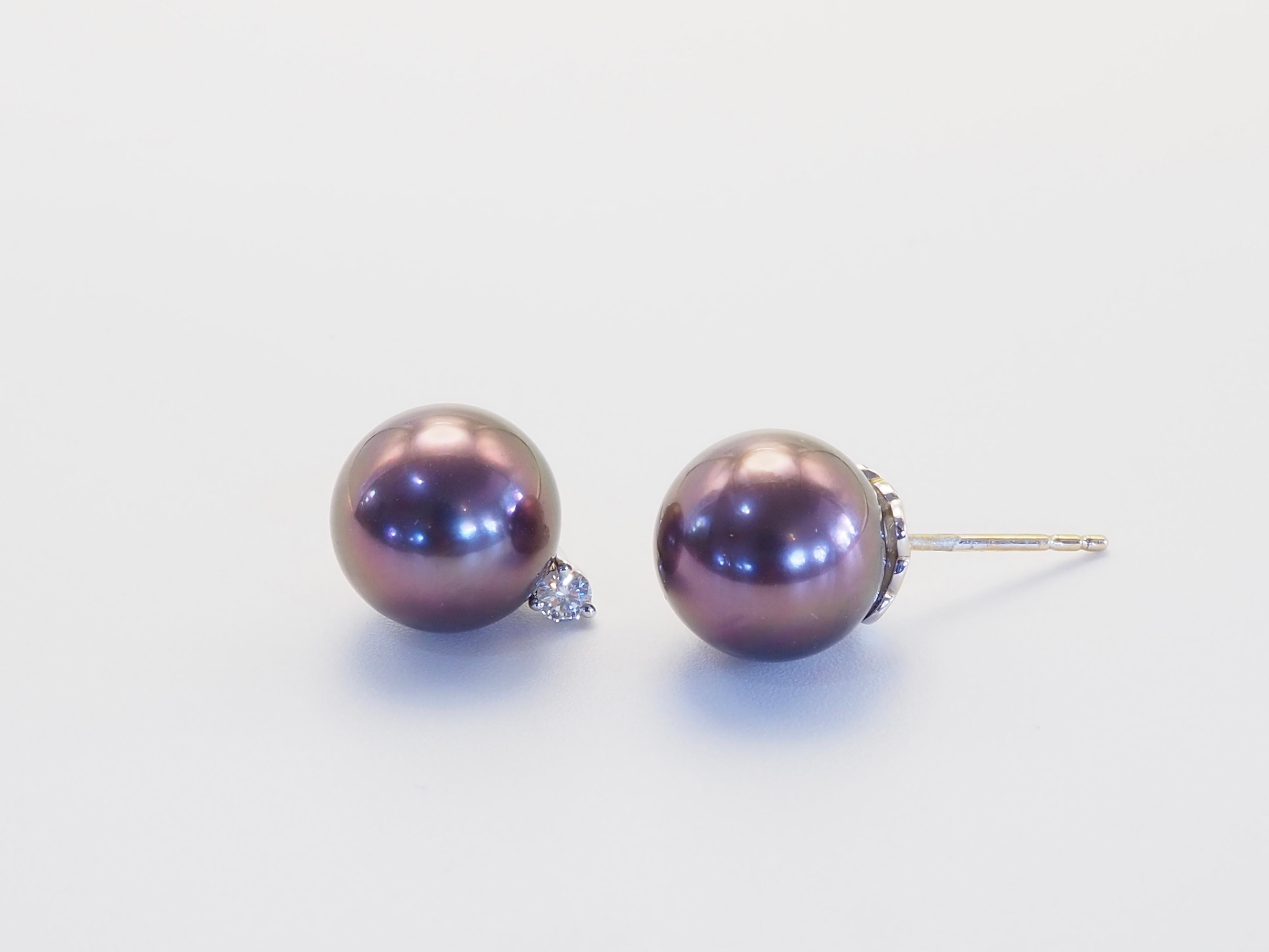 D'un luxe discret, ces boucles d'oreilles artisanales sont ornées de deux perles de Tahiti rondes de 10 mm, très prisées pour leur riche irisation naturelle dans les tons aubergine, vert paon et violet de minuit. Chaque perle est associée à un