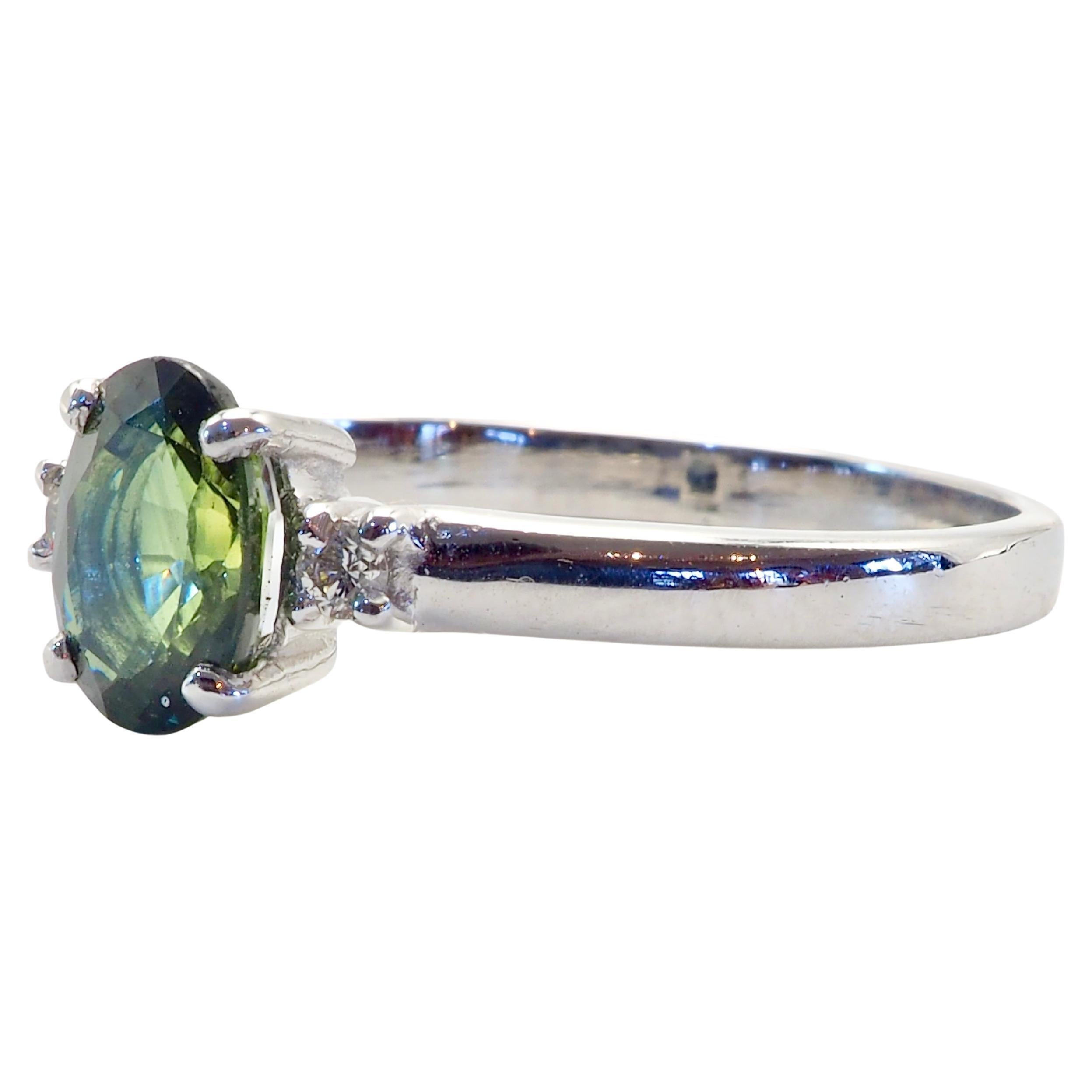 Classic and timeless band design three stone ring with a beautiful bright green oval sapphire and 2 brilliantly decent grade diamonds. The green sapphire has a yellowish tint and is bright and clear. For those who have a soft spot for alternative