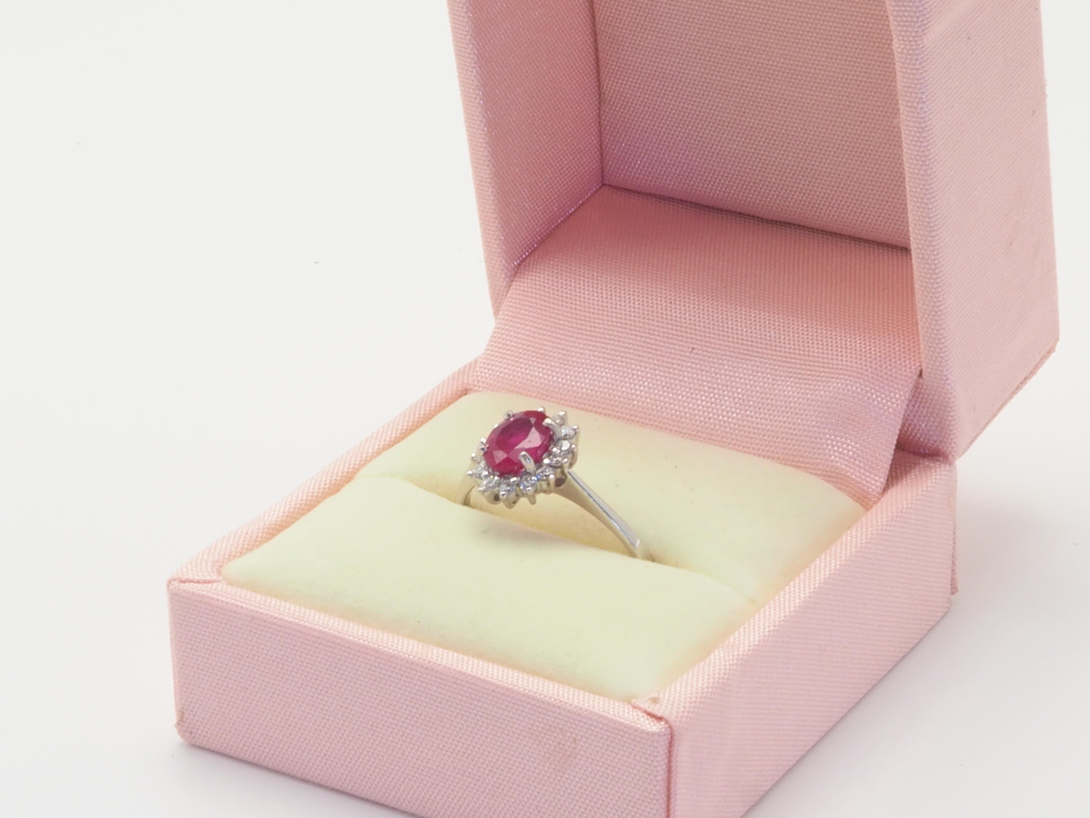 This wonderful engagement ring boasts a stunning pinkish- red oval cut ruby of 1.10 carats. The stunning oval cut ruby is refractive which is set in the middle of brilliant round cut diamonds of good grade. Natural surface inclusion is presented in