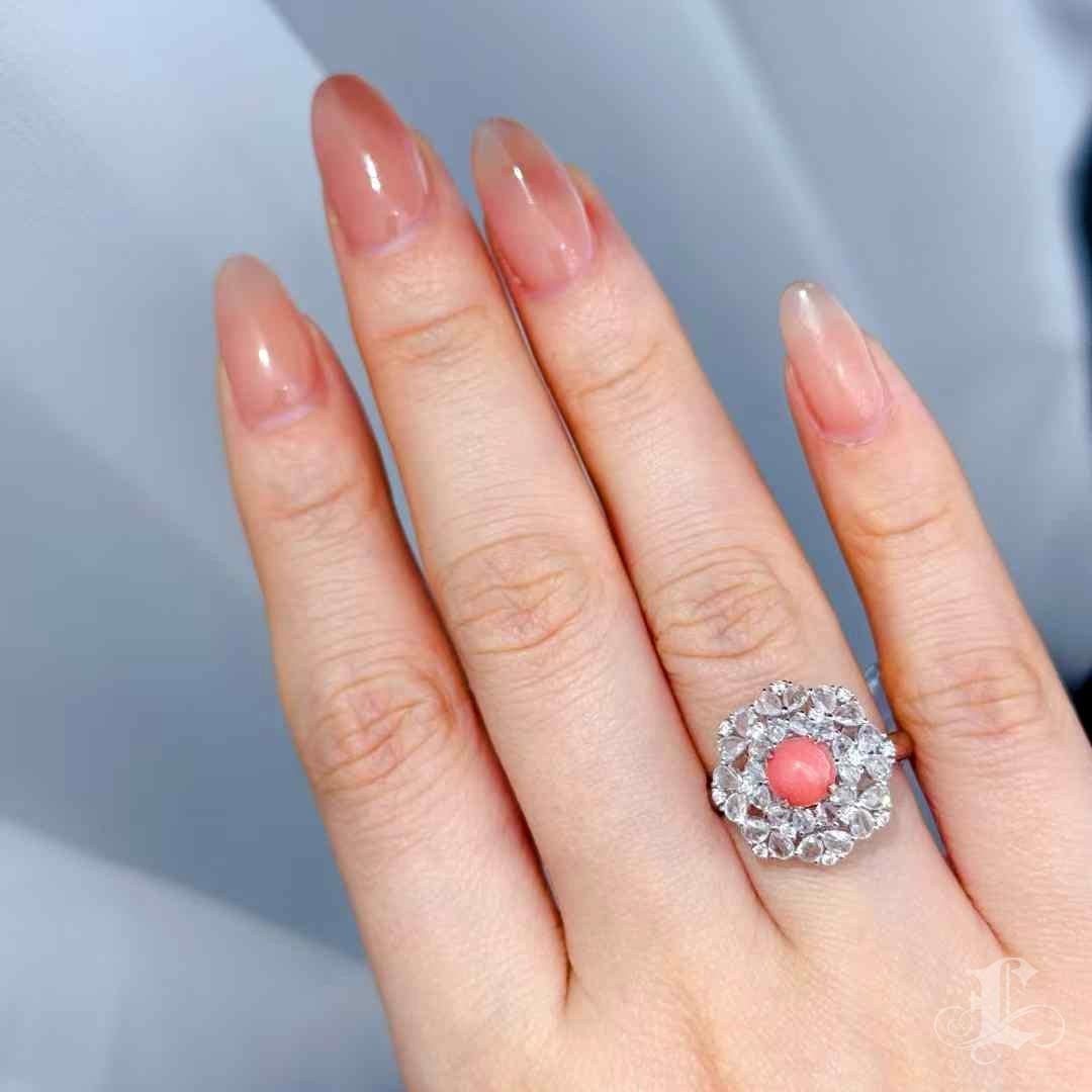 Questo anello da cocktail scultoreo, che emana un'eleganza regale, incorona una perla conchiglia naturale Flamingo Pink da 1,55 carati in un'aureola di diamanti a taglio marquise e rotondo. La perla, perfettamente rotonda e splendente con un