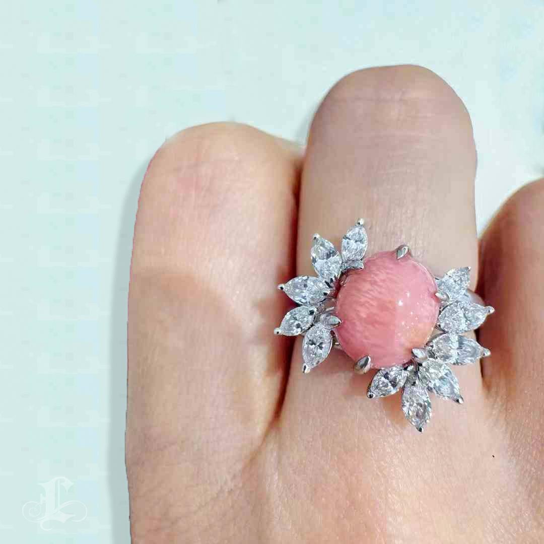 A radiant embodiment of grace and rarity, this Conchéa — Empress Flame ring centers a breathtaking 5.07ct natural conch pearl in a prized Orangey Pink hue. The pearl displays a well-defined flame pattern, a coveted optical feature that shimmers