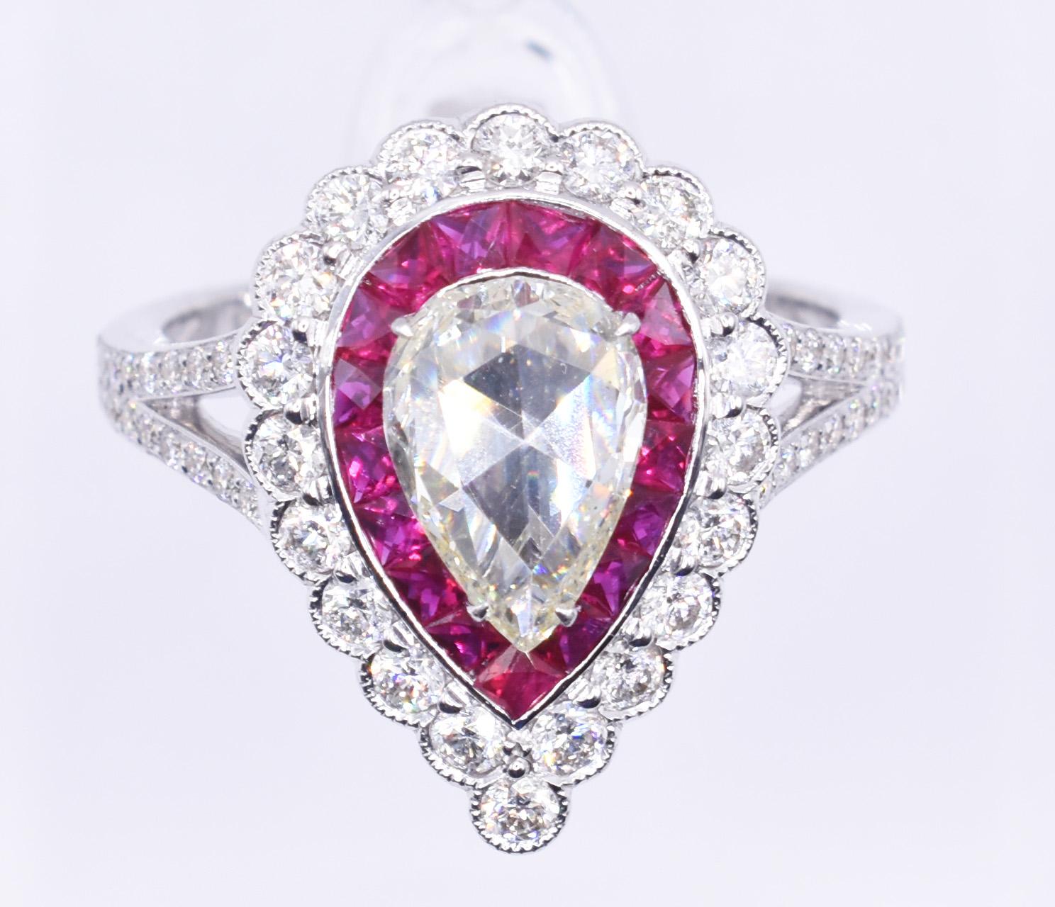 For sale is a fine quality 18k white gold diamond and ruby ring, having a 1.17ct rose cut pear shaped diamond to the centre, surrounded by French cut Burmese rubies, totaling 1.20ct, with a halo of round cut miligrain set diamonds to the edge, with