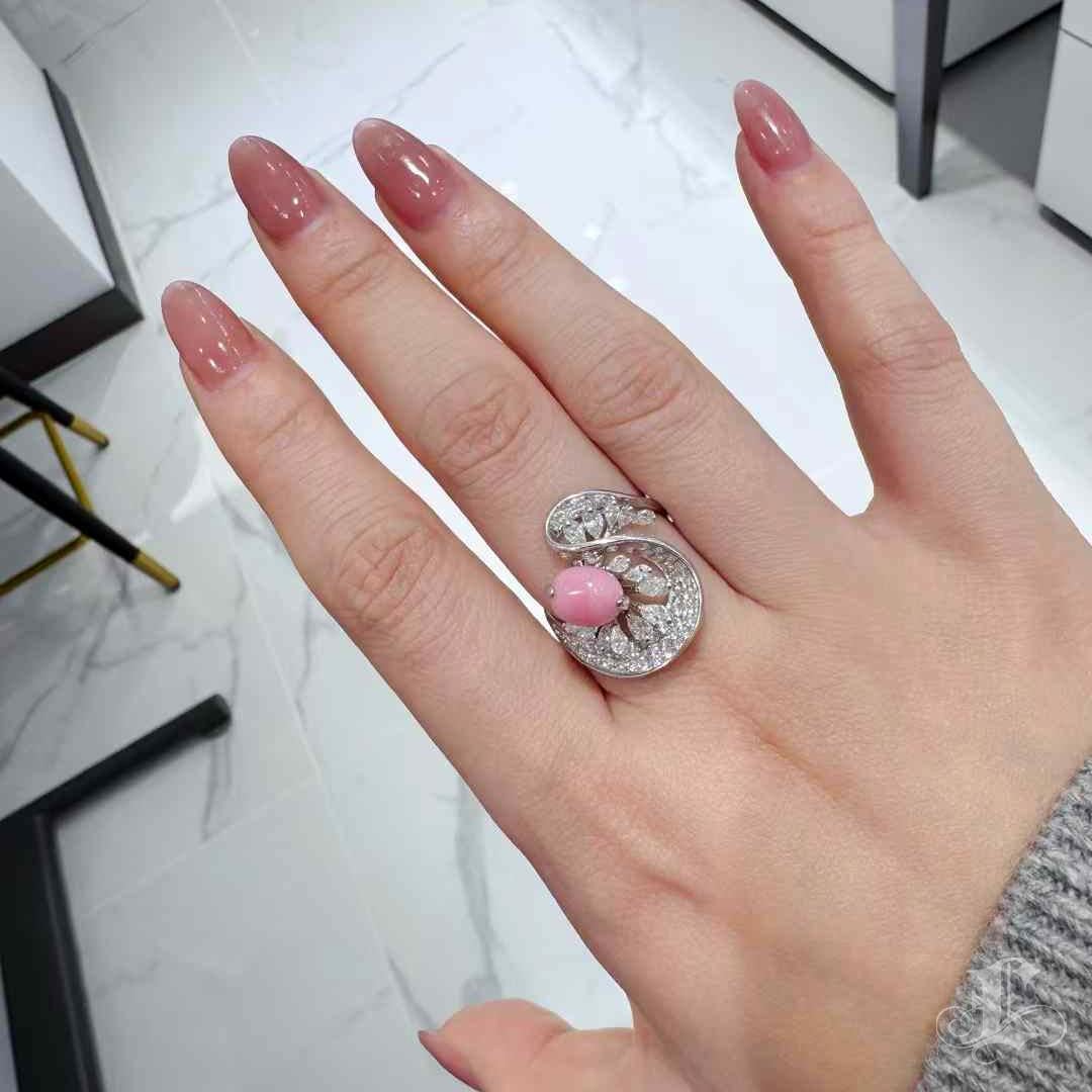 A fluid sculpture of natural grace, this ring features a 2.6-carat flamingo pink conch pearl nestled within a blossoming diamond ribbon that evokes the whisper of a petal in bloom. Set in 18K gold and accented with 1.23 carats of brilliant-cut