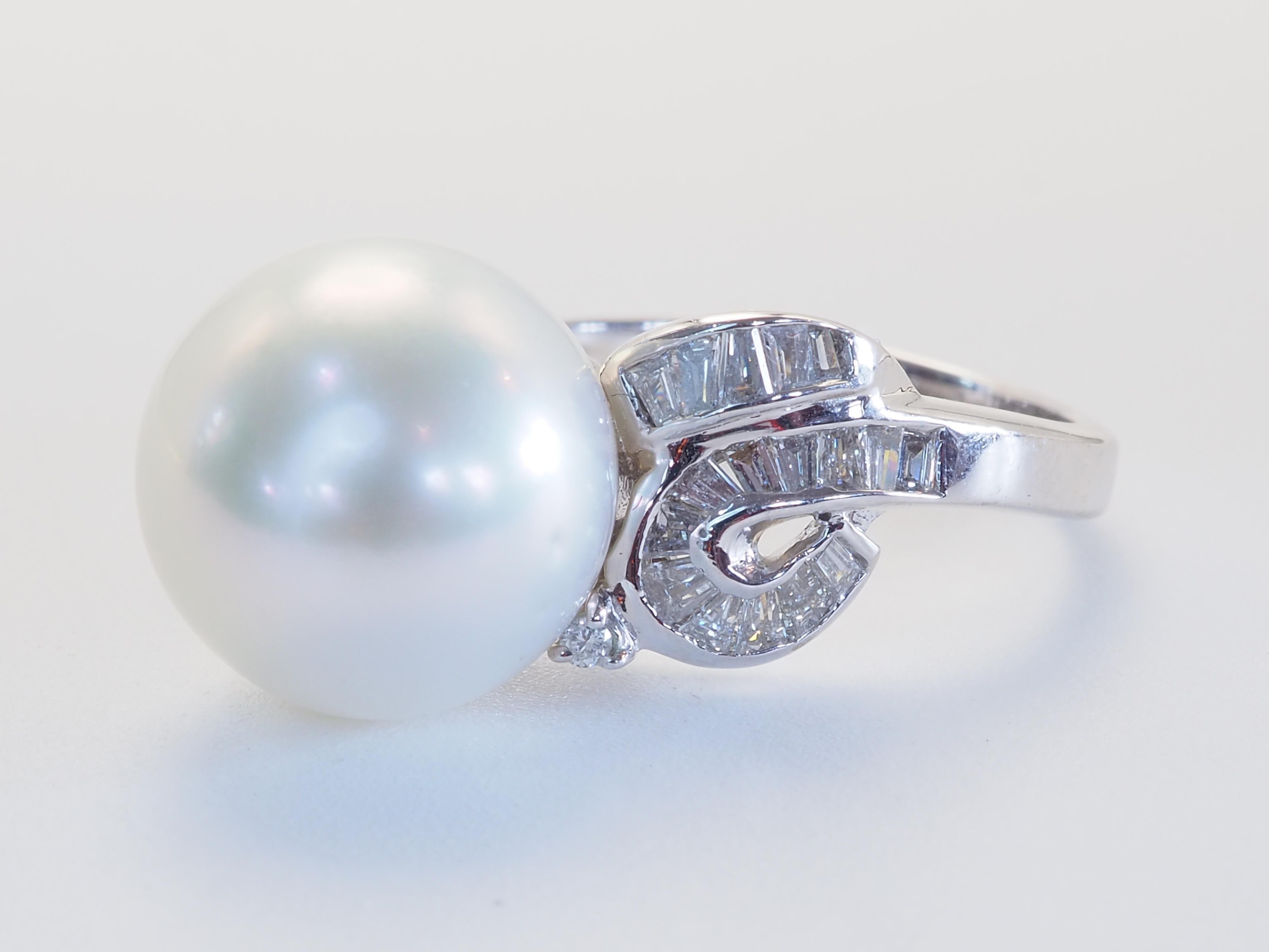 Exquisiter Ring aus 18 Karat Weißgold, gekrönt von einer leuchtenden 12-mm-Südseeperle, die für ihr natürliches Strahlen und ihre außergewöhnliche Größe bekannt ist. Der seidige Glanz der Perle wird von einer Kaskade von Diamanten im Baguetteschliff