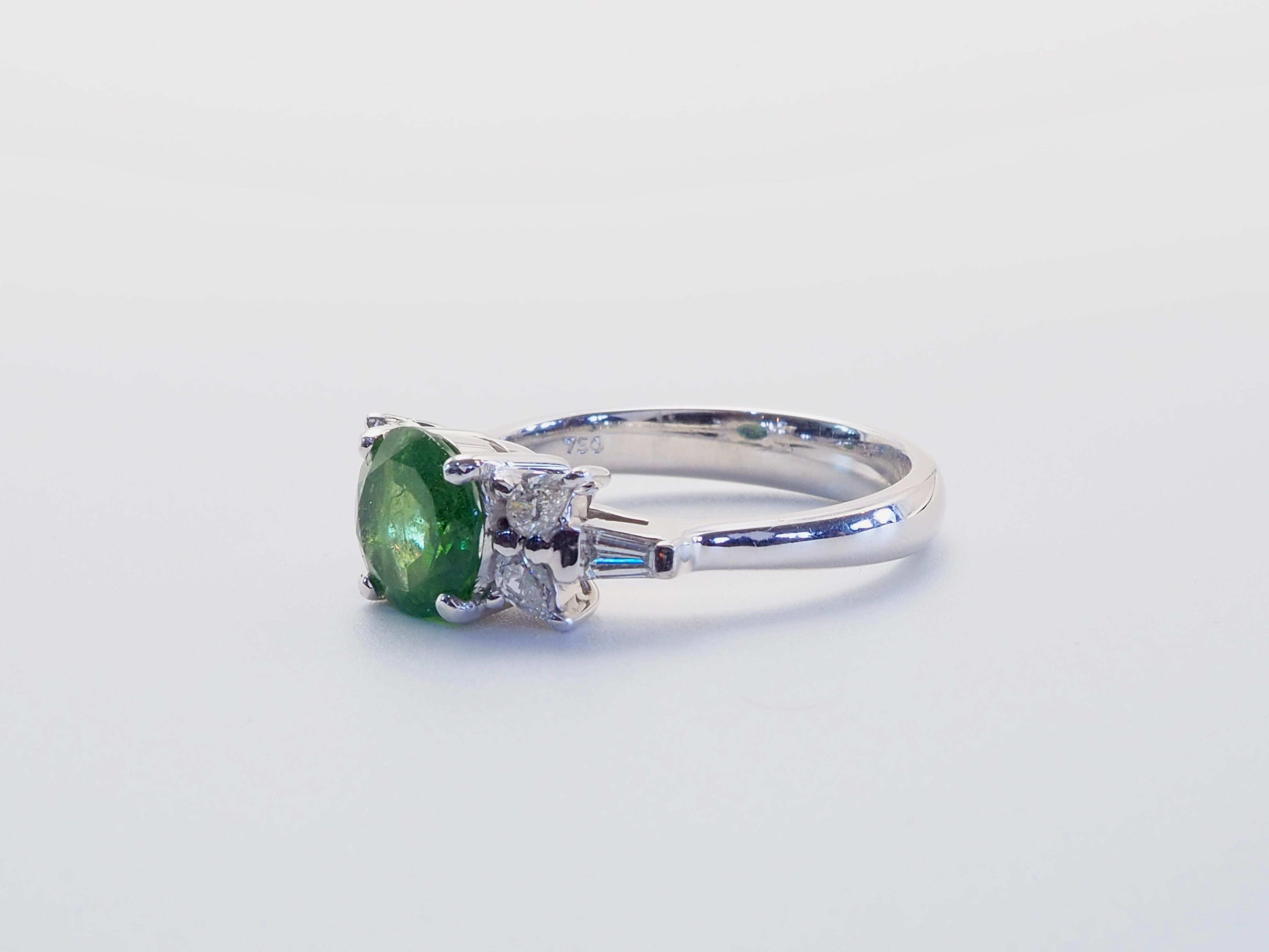 A striking composition of color and clarity, this refined ring showcases a 1.54-carat round-cut tsavorite garnet, celebrated for its vivid green hue and exceptional brilliance. The center stone is securely set in 18k white gold, offering a sleek,