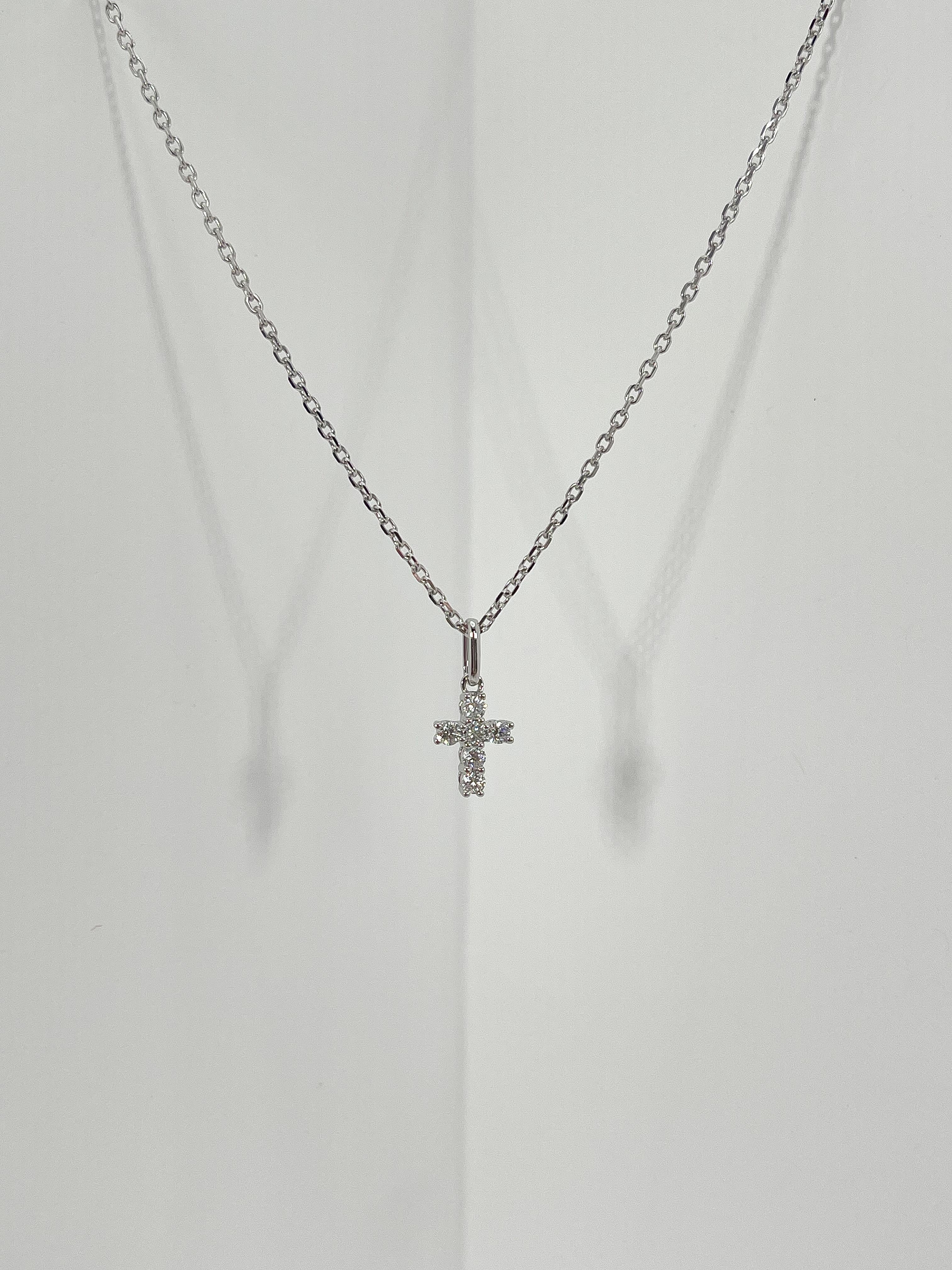 18K white gold .20 CTW diamond cross necklace. The diamonds in the pendant are all round, the pendant measures to be 8.5mm x 6.5mm, has a lobster clasp to open and close, pendant comes on an 18-inch diamond cut cable chain, and has a total weight of
