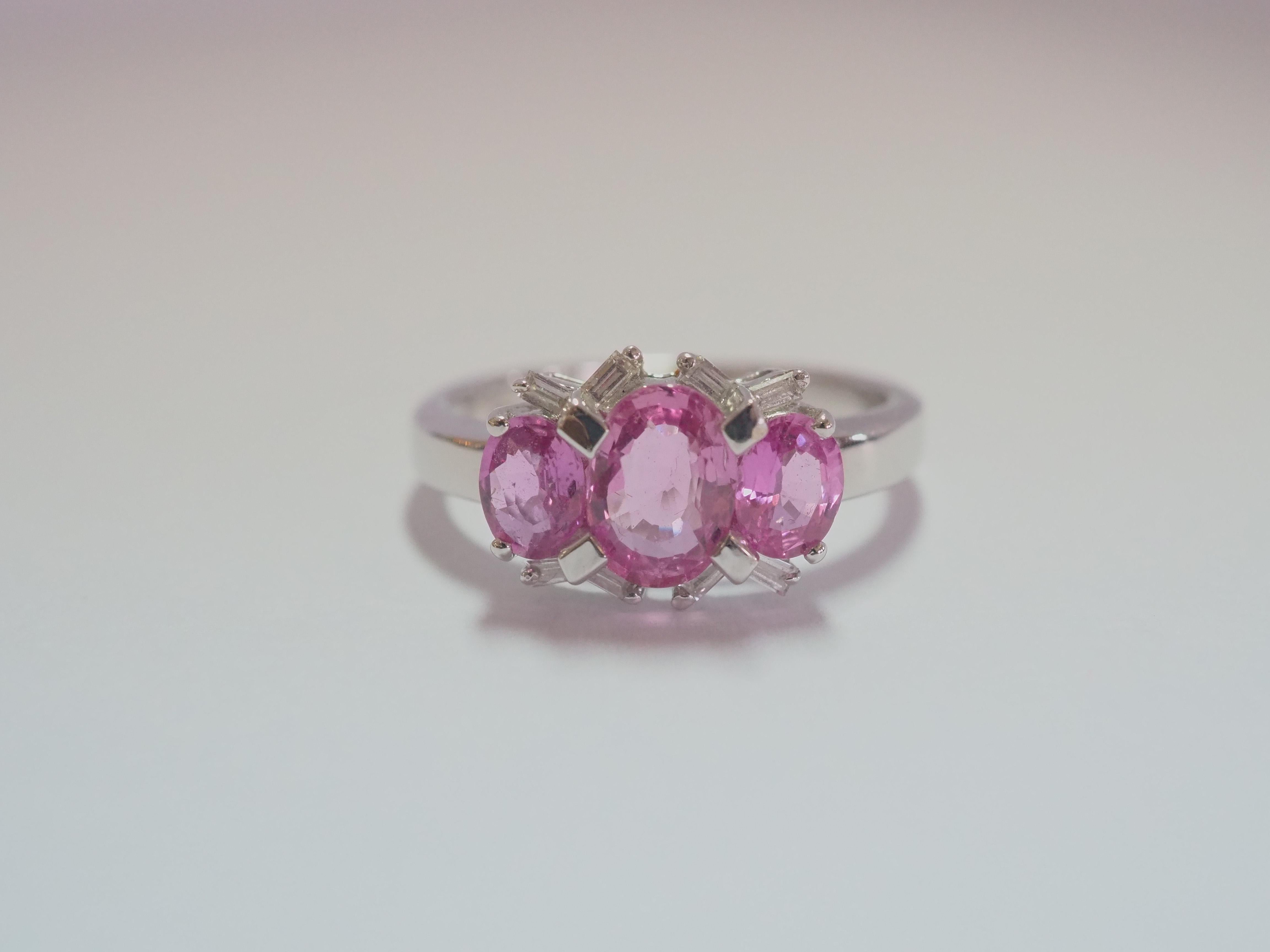 This quality and beautiful engagement piece is an 18K white gold fine quality pink sapphire and diamond ring. 3 bubblegum oval pink sapphires are set meticulously and at the center is the largest one. There are 8 of baguette cut diamonds at decent