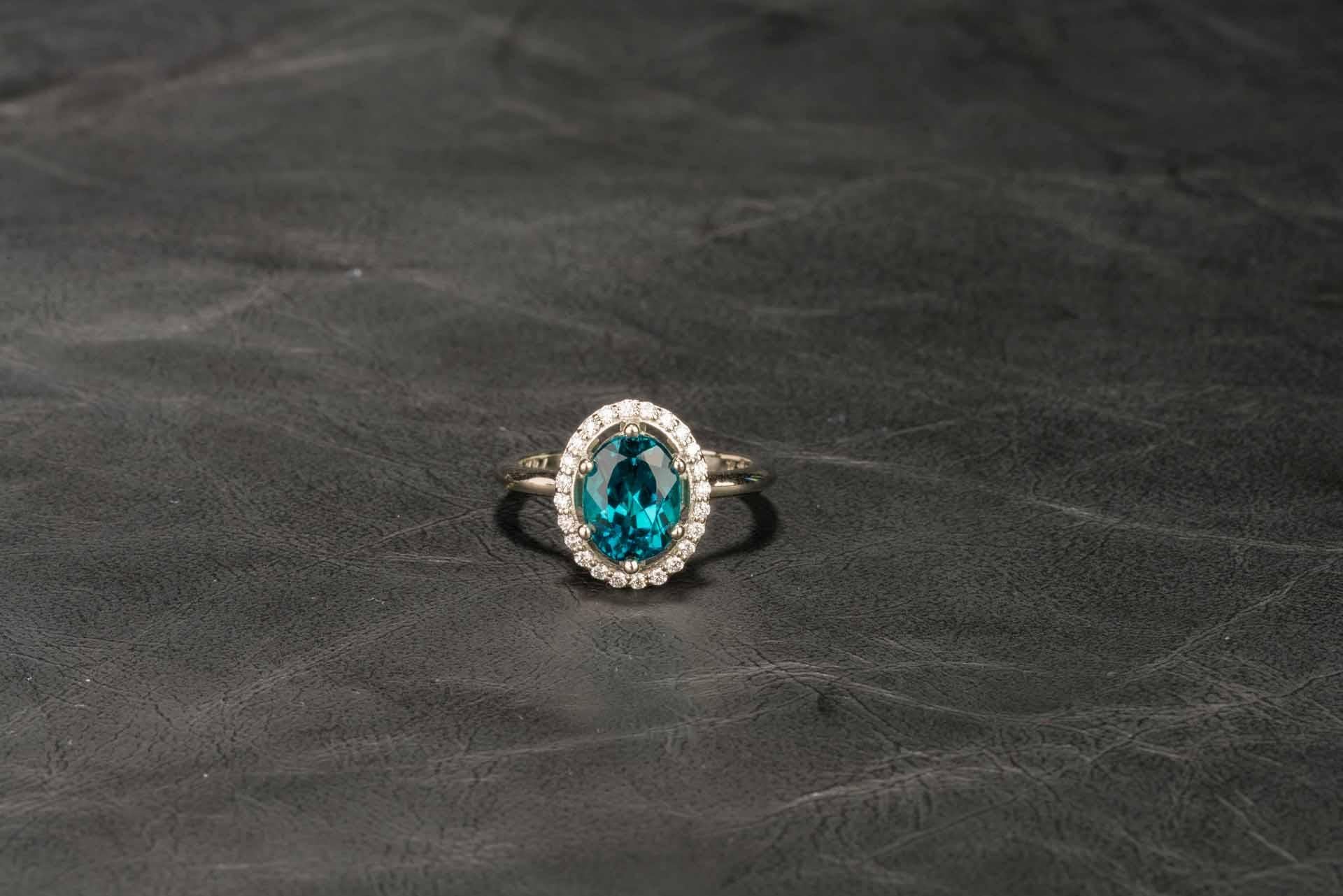 An 18k white gold ring set with a 2.47 carat Brazilian indicolite tourmaline with a halo of 0.24 total carat weight round full cut white diamonds, F color, VS clarity, ring size 6.75. Designed and made by llyn strong.