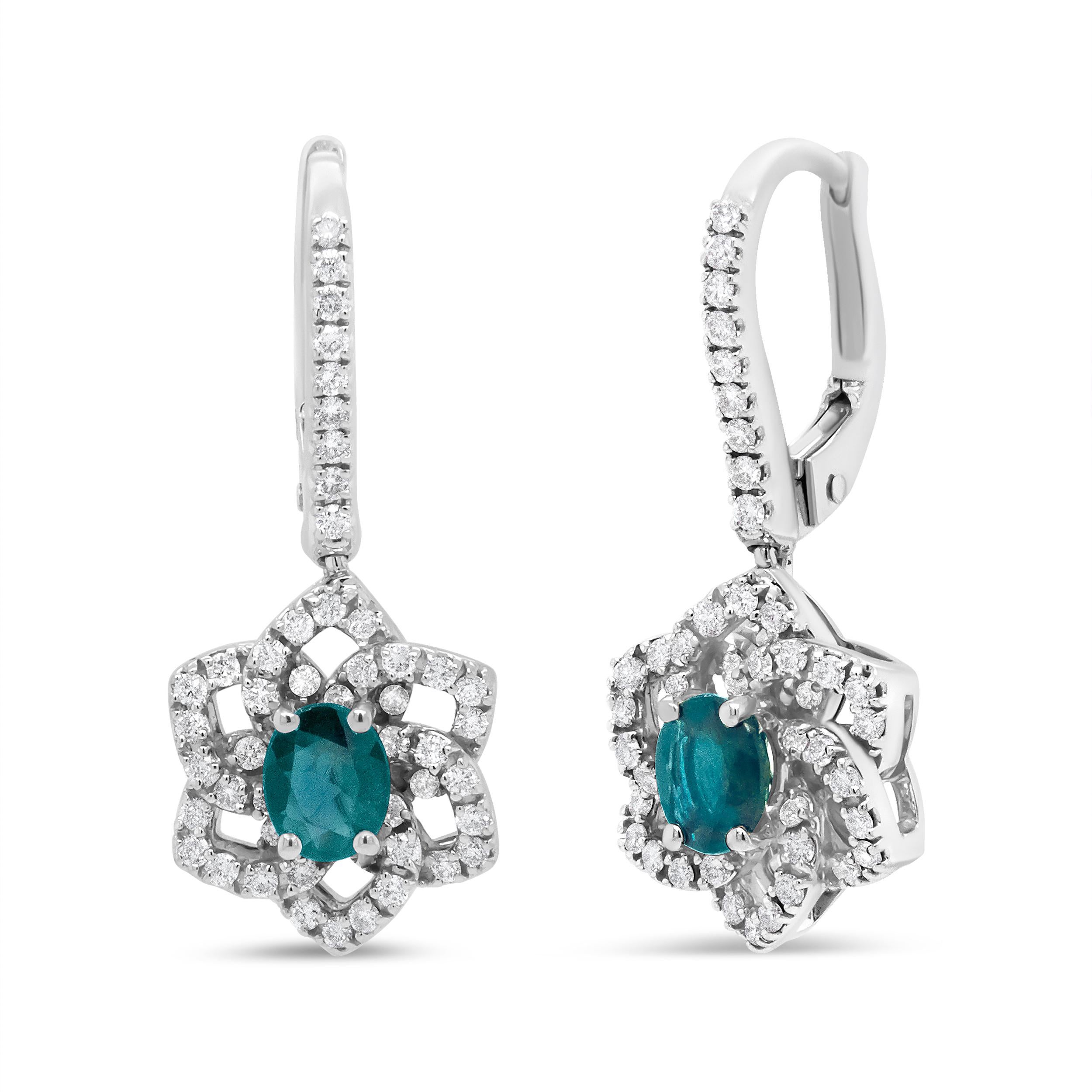 Electrifying color sparkles from this pair of 18k white gold dangle drop earrings in the form of a blazing blue 4.94 x 3.96mm oval sapphire in a 4-prong setting. These are natural, color-treated gemstones of dazzling sparkle. A starburst silhouette
