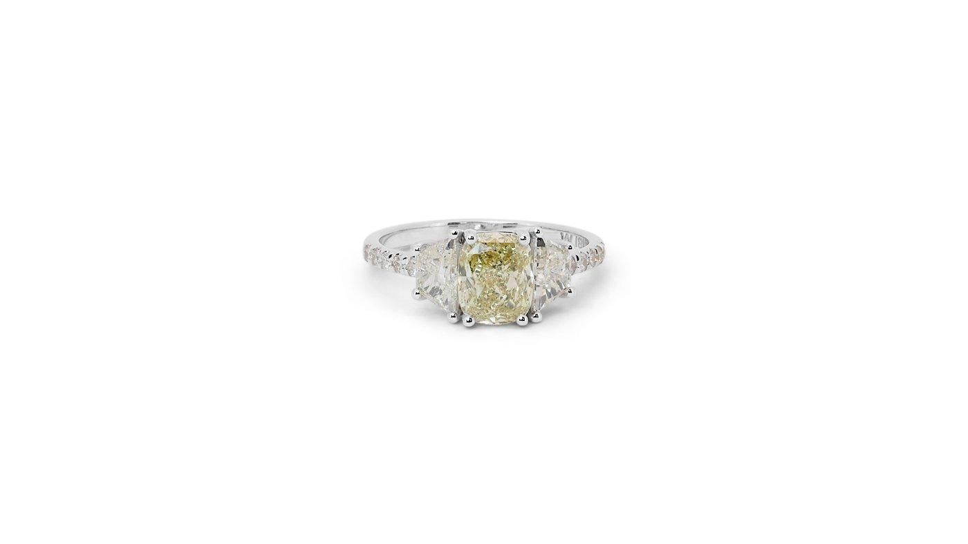 Ein atemberaubender Ring mit drei Steinen und einem schillernden natürlichen Diamanten von 1,51 Karat in Kissenform. Er hat 0,77 Karat seitliche Diamanten, die seine Eleganz noch unterstreichen. Das Schmuckstück ist aus 18 Karat Weißgold mit einer