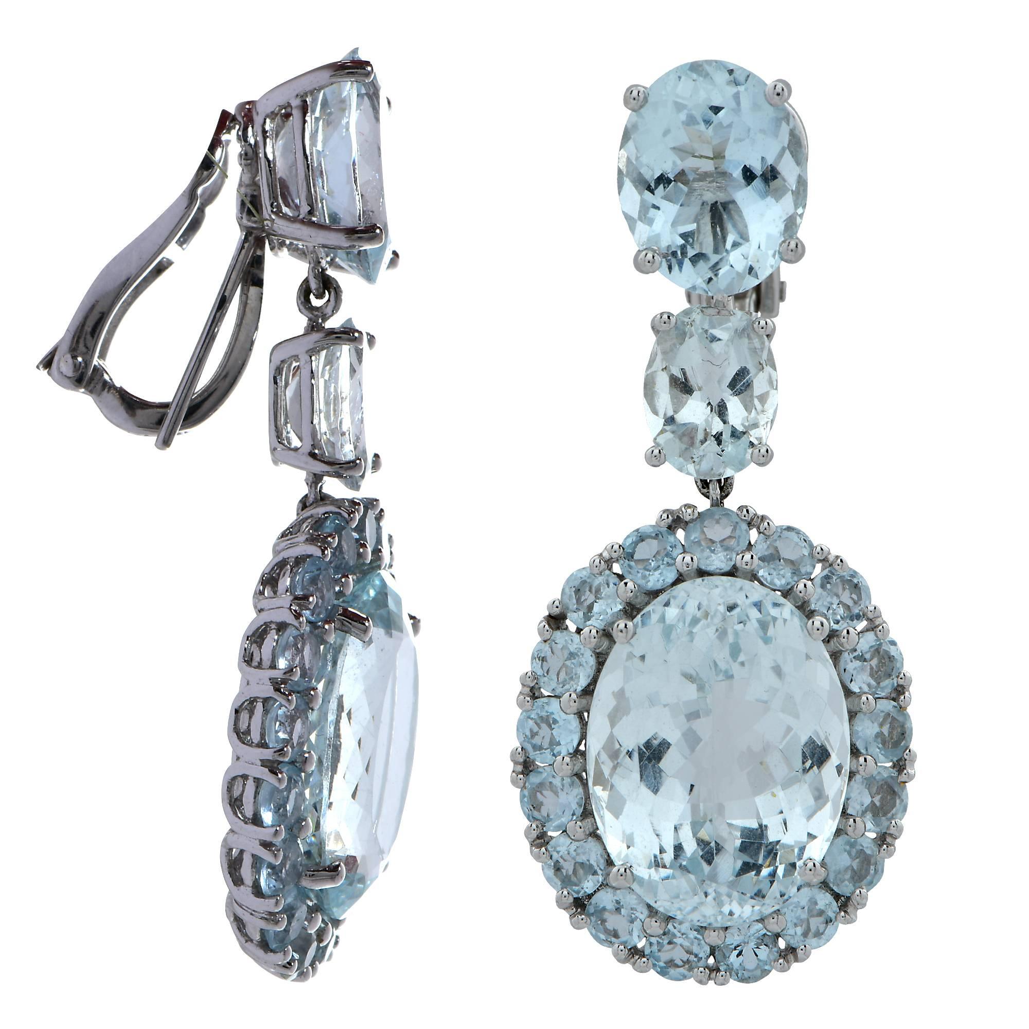 18k white gold dangle earrings featuring two brilliant cut oval Aquamarines weighing approximately 15 carats total, accenting the center Aquamarines are 38 round and oval cut Aquamarines weighing approximately 15 carats. The earrings measure 1.7