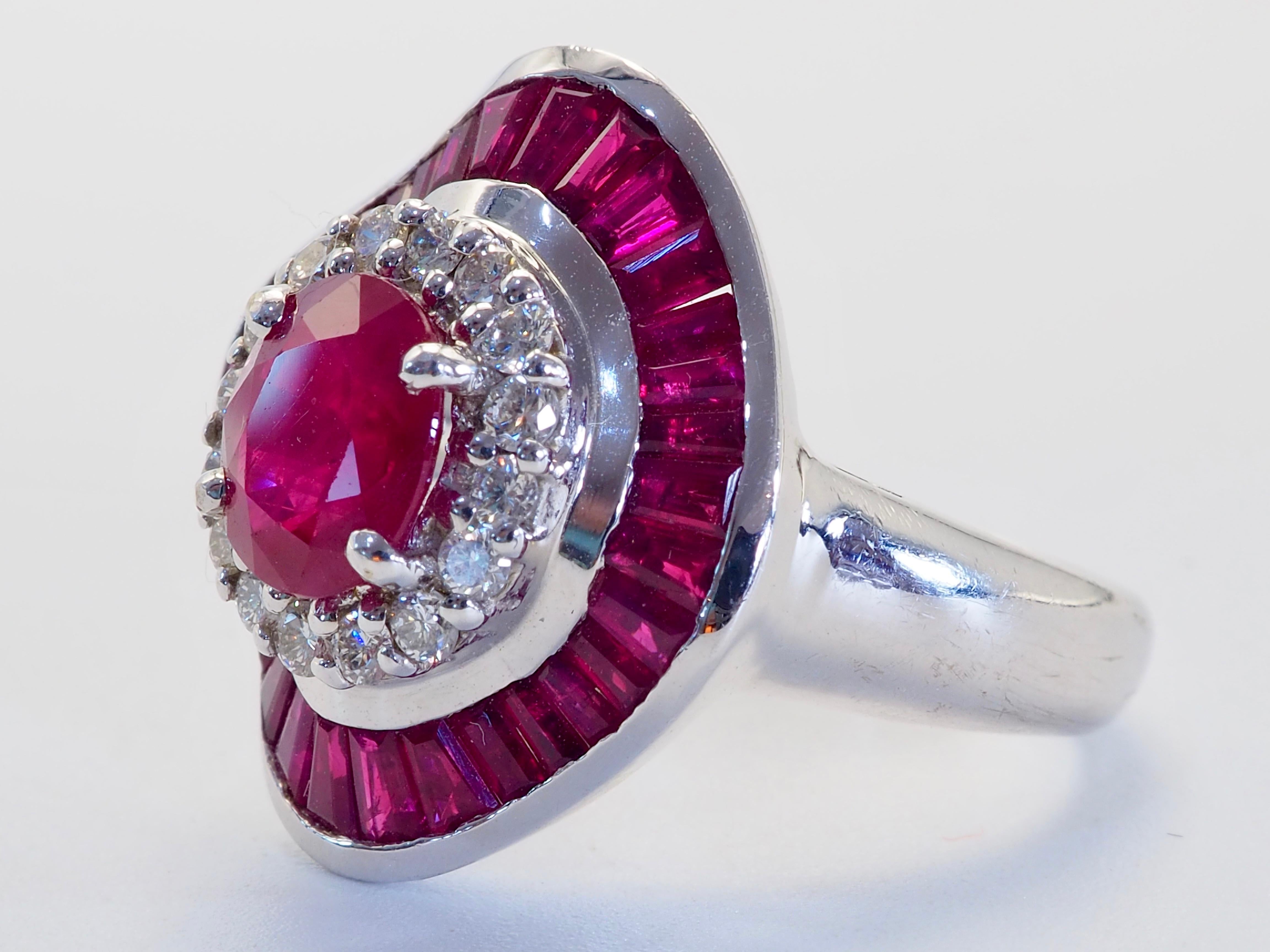 Uno splendido anello con rubino rosso scuro. Il rubino ovale ha una buona saturazione di rosso e viola con inclusioni naturali. I diamanti qui presenti sono brillanti e di ottima qualità, chiari e incolori. I rubini di taglio calibro circostanti