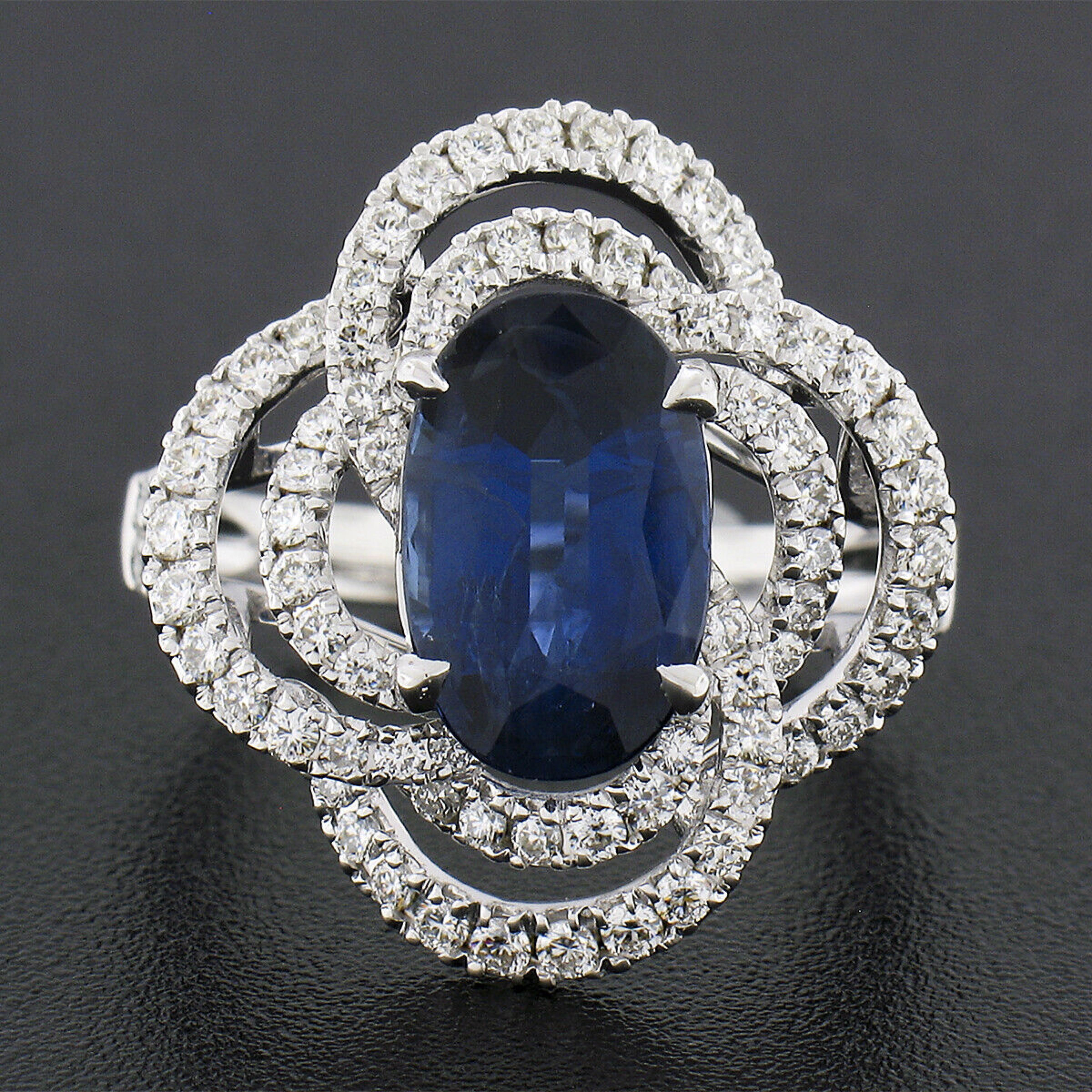 Here we have a truly breathtaking cocktail ring that was crafted from solid 18k white gold featuring a GIA certified, natural sapphire stone neatly prong set at the center of a fiery diamond drenched infinity swirl design. The elongated oval cut