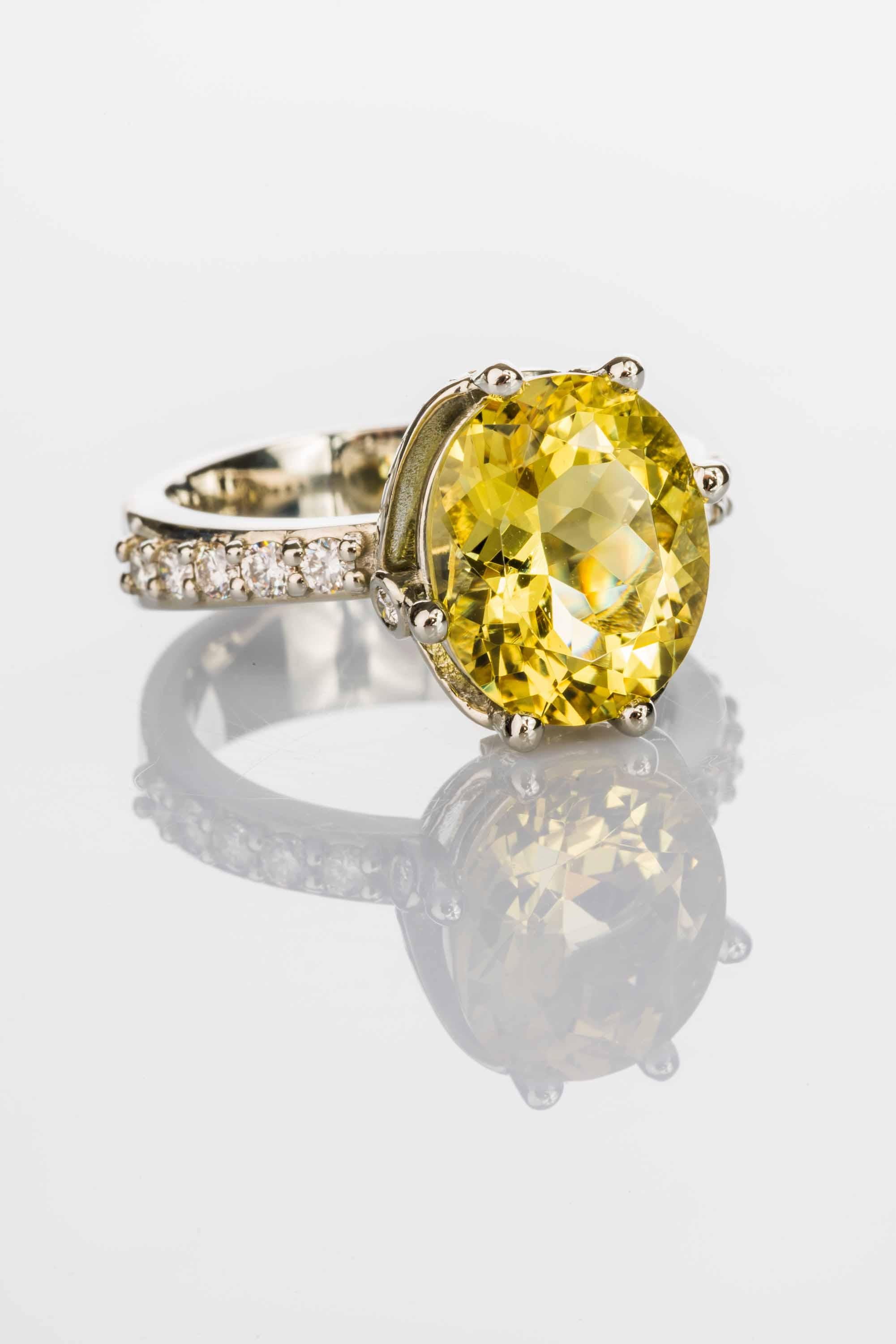 An 18k white gold ring prong set with an oval cut natural Nigerian yellow beryl, 4.70 total carat weight and fourteen round full cut white diamonds F color VS clarity 0.55 total carat weight, ring size 7. This ring was custom designed and made by