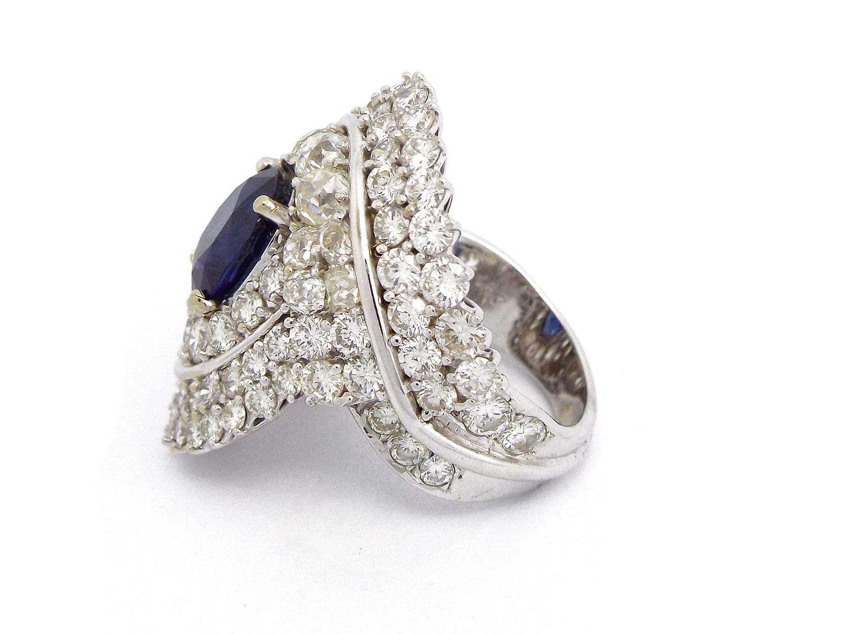 Diamond Ring centering a cushion sapphire, weighing approximately 5.08 carats, within a scrolled surround of old mine and round brilliant-cut diamonds; estimated total diamond weight: 9.60 carats; mounted in 18k white gold; 
Total Weight: