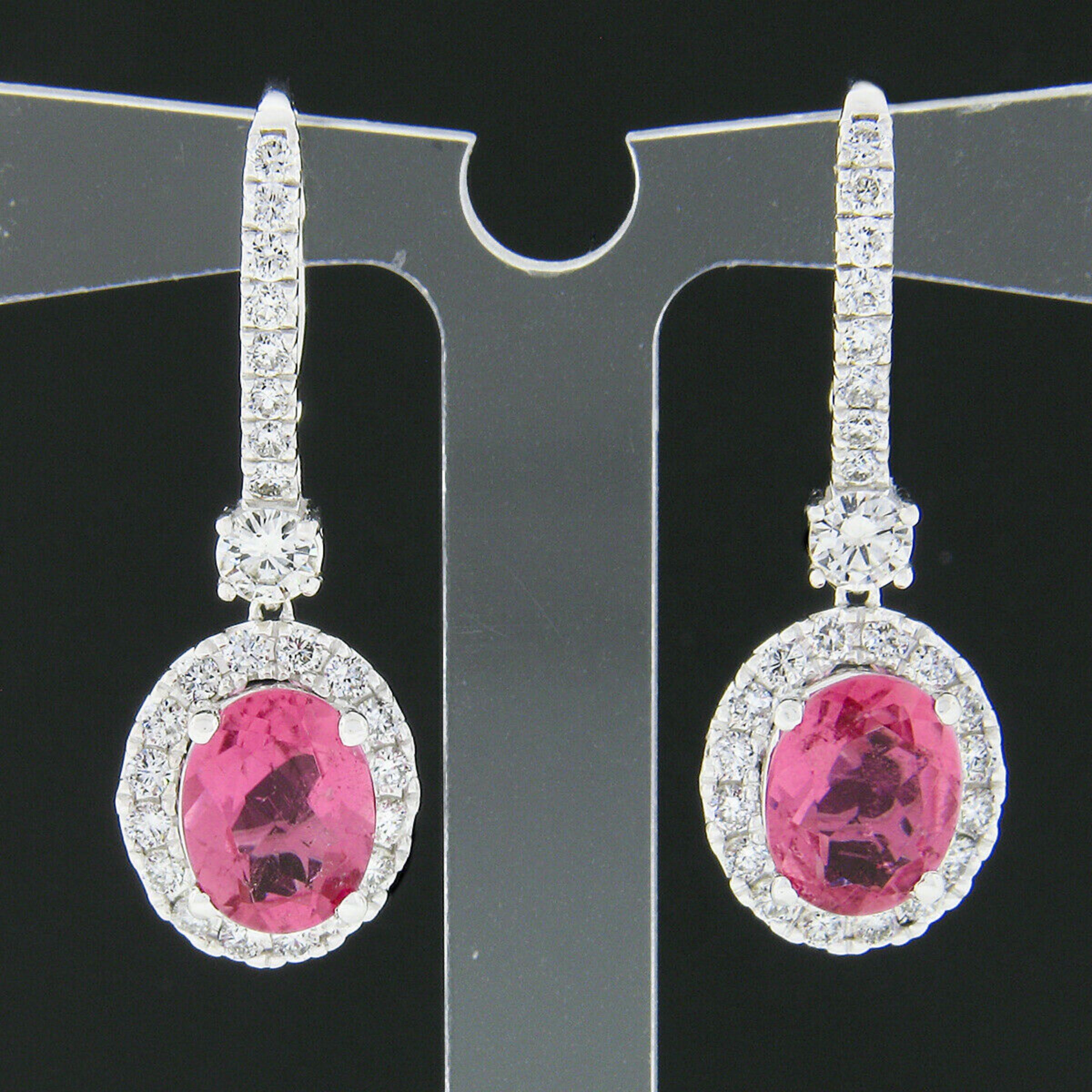 These gorgeous earrings were crafted from solid 18k white gold and feature a drop dangle style that carries a stunning pink tourmaline with fine round brilliant cut diamonds throughout. The top of the earrings are lined with diamonds with a large