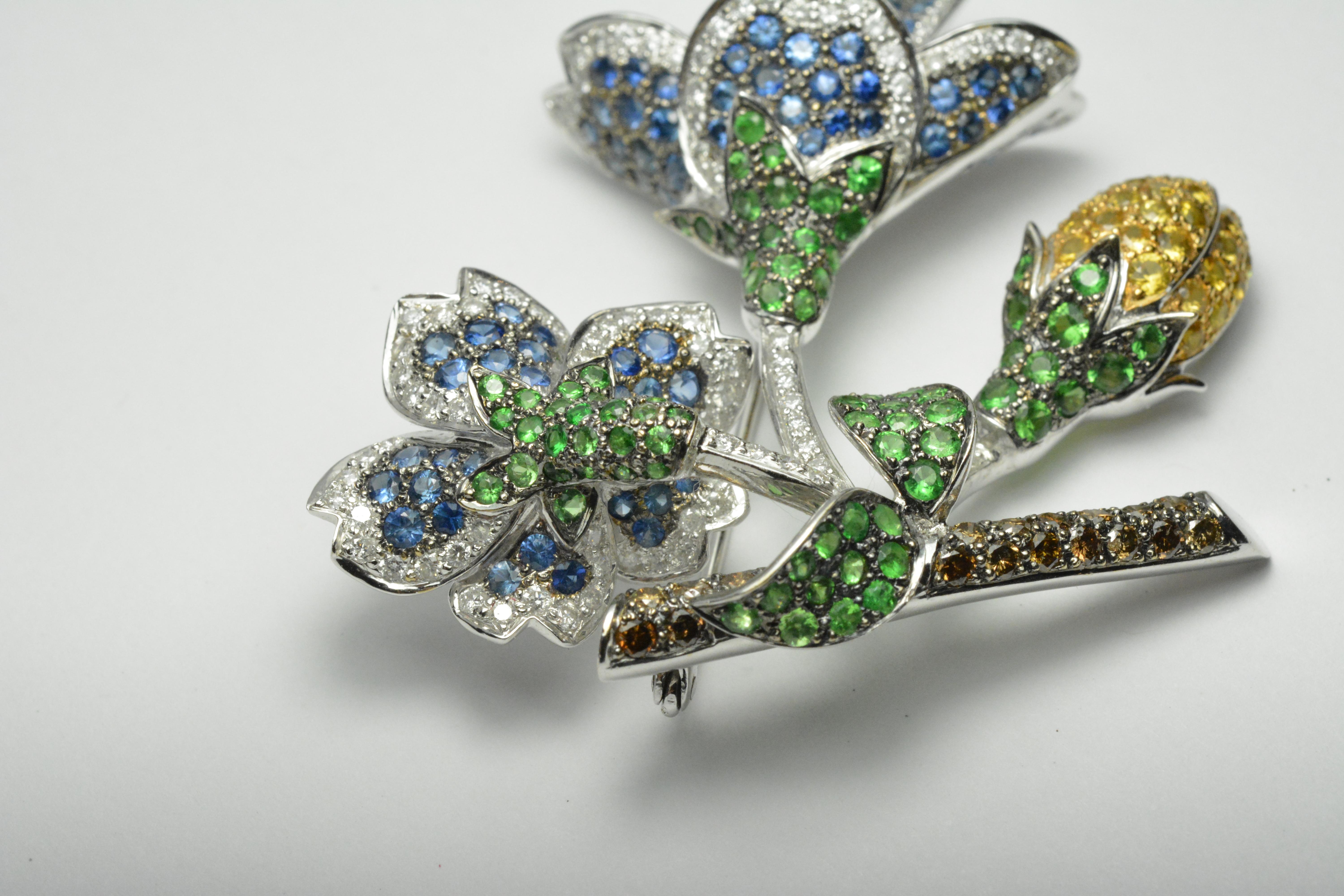 Colored stone and diamond custom brooch in 18k white gold.

Tests 18k and weighs 23 grams.

There is 7.25 total carats of round brilliant cut diamonds, G color, VS to Si clarity.

The other stones are natural  yellow sapphires, green tsavorite and