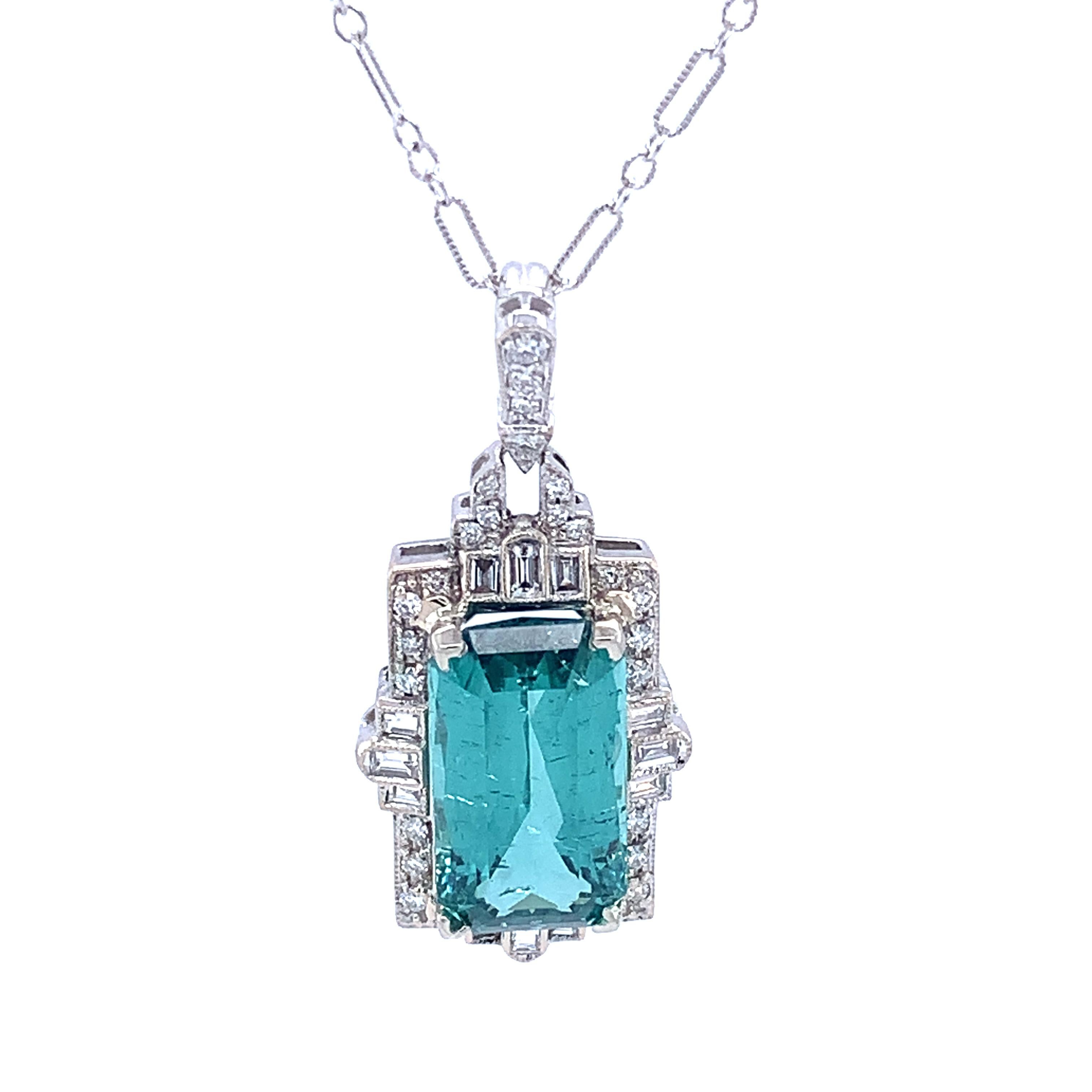18K white gold pendant featuring a spectacular teal green tourmaline weighing 9.60 carats. The tourmaline is a rectangular radiant with blue-green color. The color is more like the photo on the grey bust, not as blue as shown in the light box. The