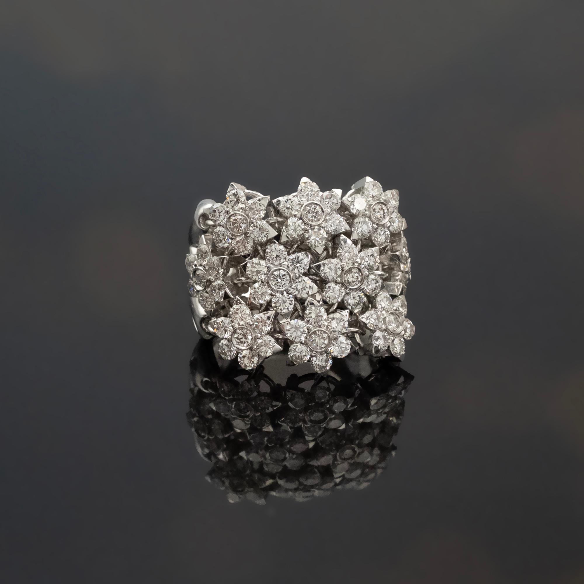 Dieser breite Ring von Claris.A ist aus 18 Karat Weißgold gefertigt und besteht aus mehreren diamantbesetzten Blumenmotiven. Jede Blume wird einzeln montiert, wodurch kleine Zwischenräume entstehen, die der Oberfläche eine dimensionalen Qualität