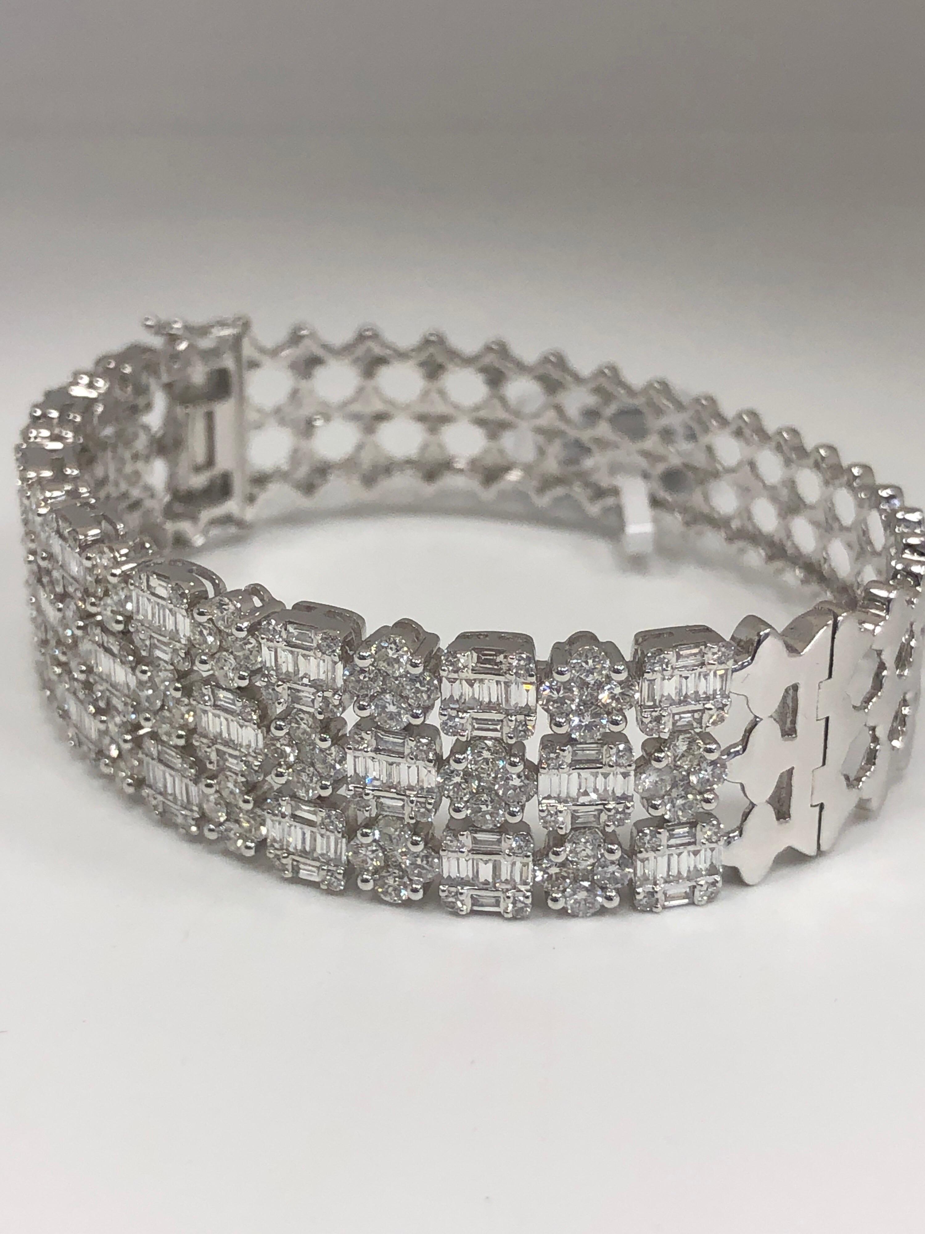 The hinged cuff, crafted in 18K white gold, is mounted in cluster design with round brilliant cut and baguette diamonds totaling 6.79 carats.