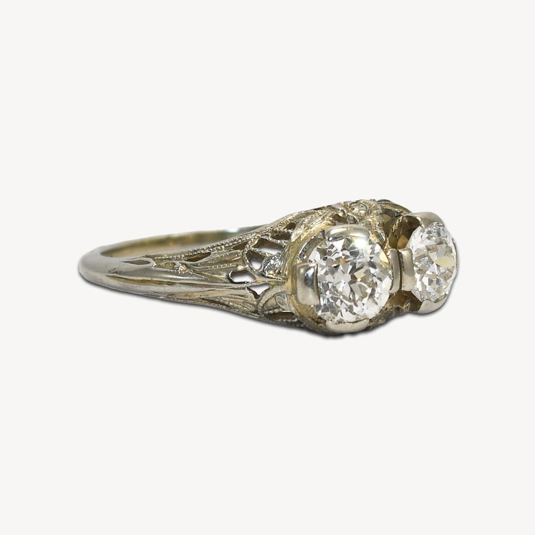 Antique 18k white gold and diamond ring.
Stamped 18k and weighs 3 grams. Beautiful open metalwork on the sides.
Both diamonds are old-euro cuts. One diamond is a .60 carat i color, Si1 clarity.
The other is .39 carats, H color, VS clarity. The ring
