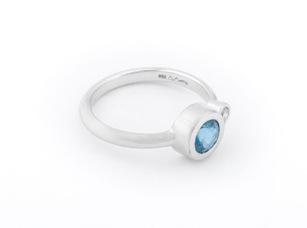 18K white gold ring, featuring one round aquamarine crystal weighing approx. 1.00 carat, adorned with a round diamond weighing approx. 0.10 carat, marked, 