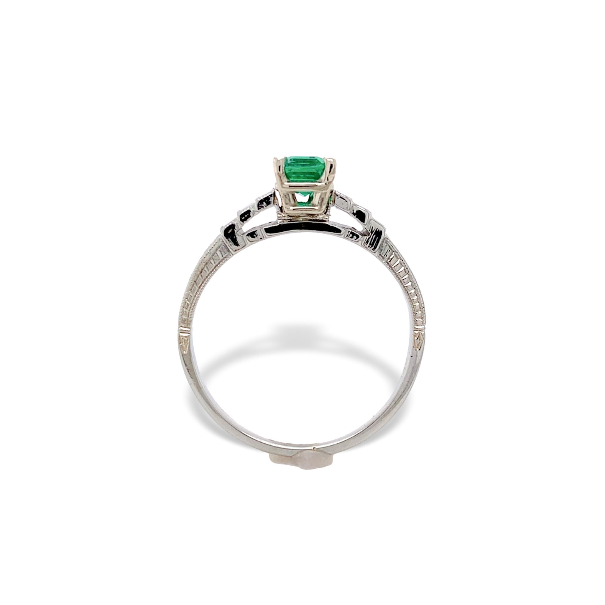 Anello Art Deco in oro bianco 18 carati con smeraldo autentico estratto dalla terra. Il fine smeraldo misura circa 5,3 mm x 4 mm e ha un colore verde erba brillante. I lati sono incisi a mano e il disegno è molto nitido, in ottime condizioni.
