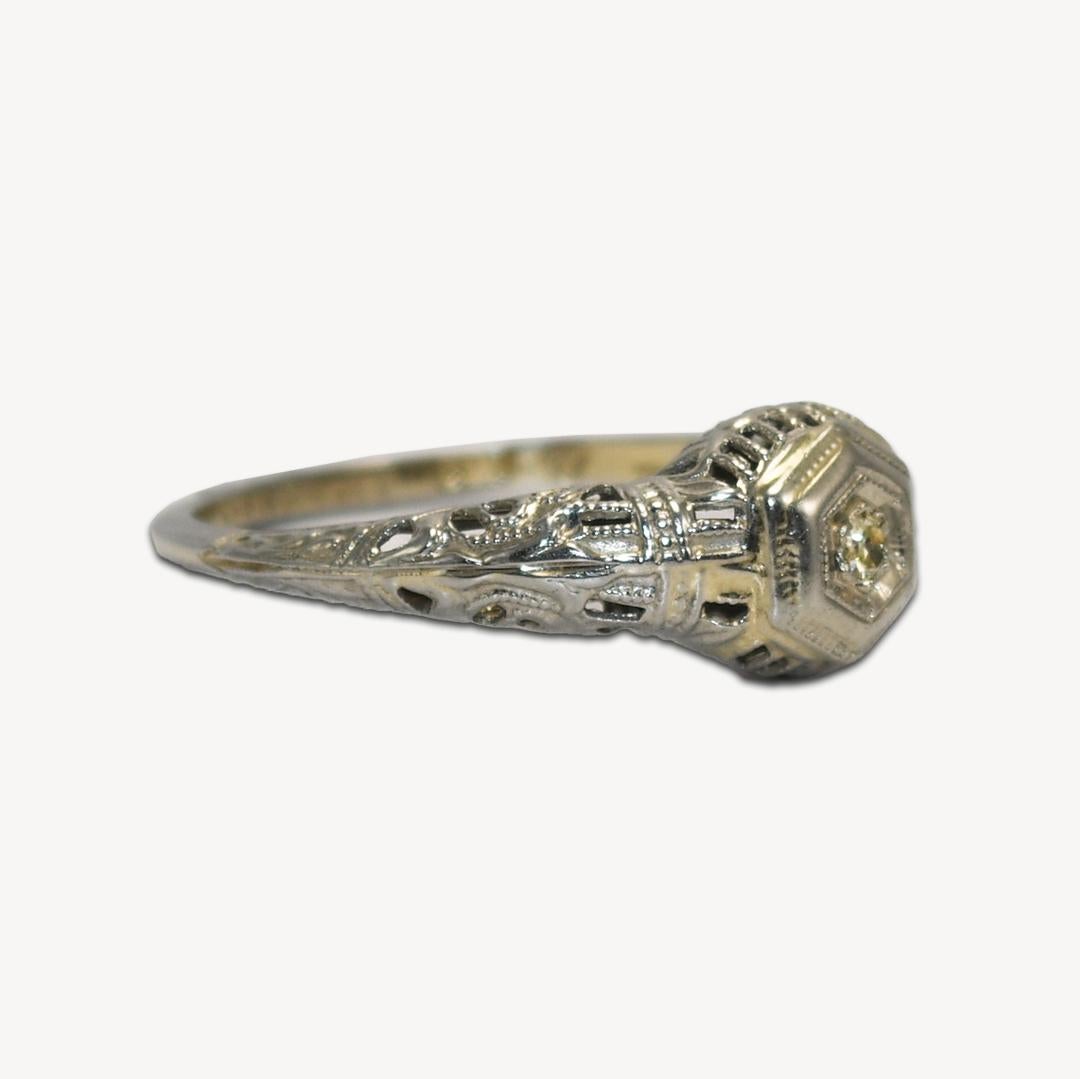 Ladies Art Deco ring in 18k white gold with diamond. 
The ring is marked 18k and weighs 1.6 grams. 
The diamond is a light yellow single cut. 
Fancy open metalwork on the sides and top of the ring. 
The ring is in excellent condition. 
The ring size