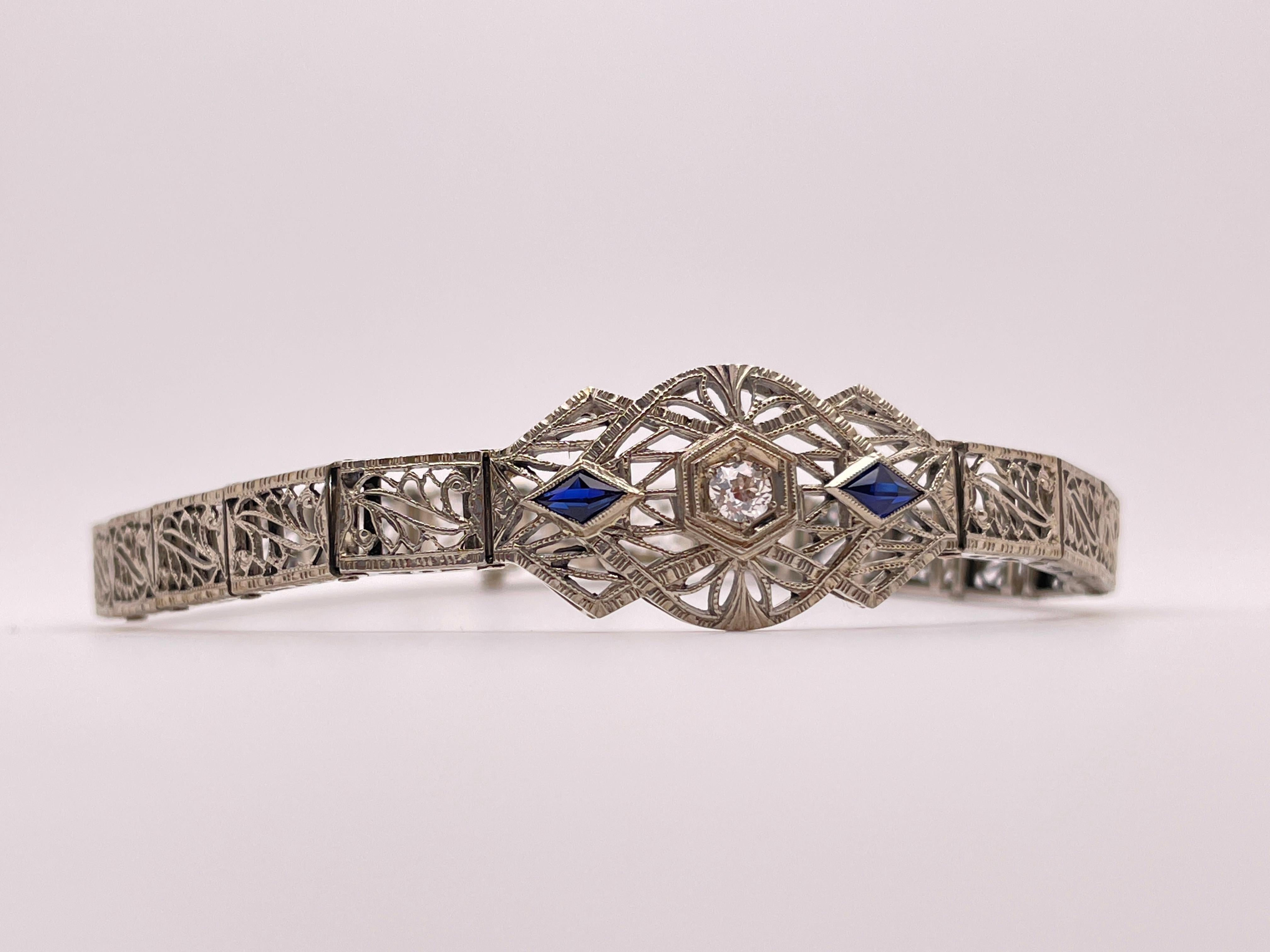 Un magnifico braccialetto originale Art Deco in oro bianco 18 carati con diamanti e zaffiri in filigrana che misura 7,60 pollici. Composto da maglie con design a filigrana incernierate singolarmente e da un pezzo centrale montato con due zaffiri a