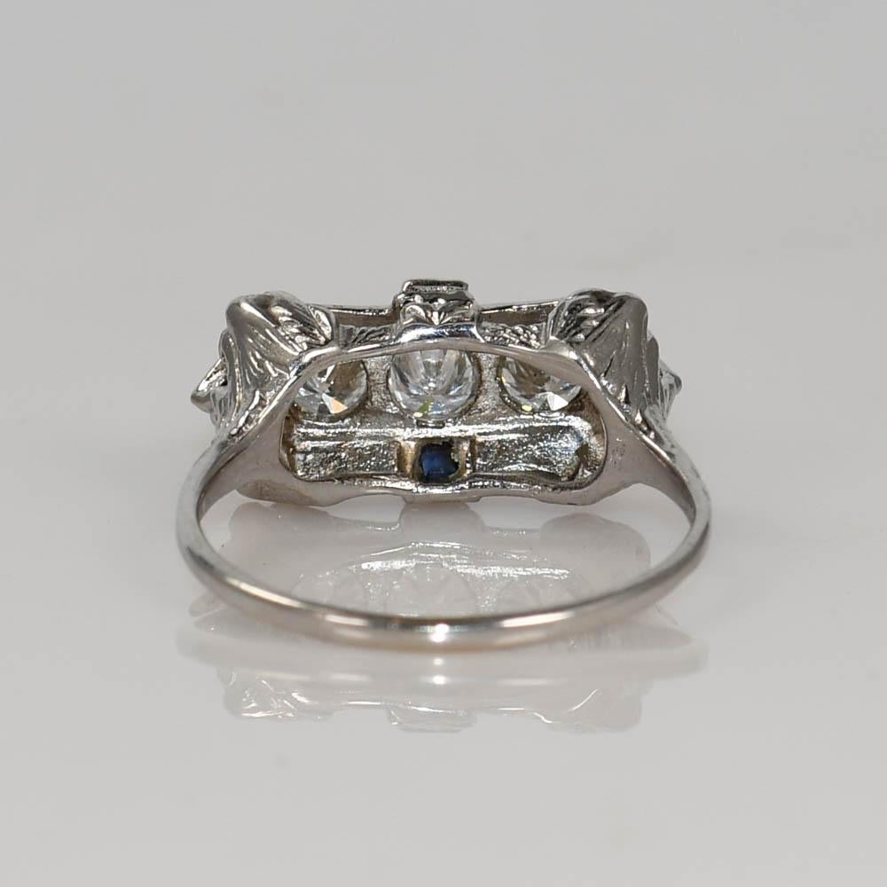 Art Deco style diamond and sapphire ring in 18k white gold.
Stamped 18k and weighs 3.6 grams.
The three diamonds are round brilliant cuts, .60 total carats, G color, VS clarity, and good cuts.
There are four blue sapphires on the sides.
The top of