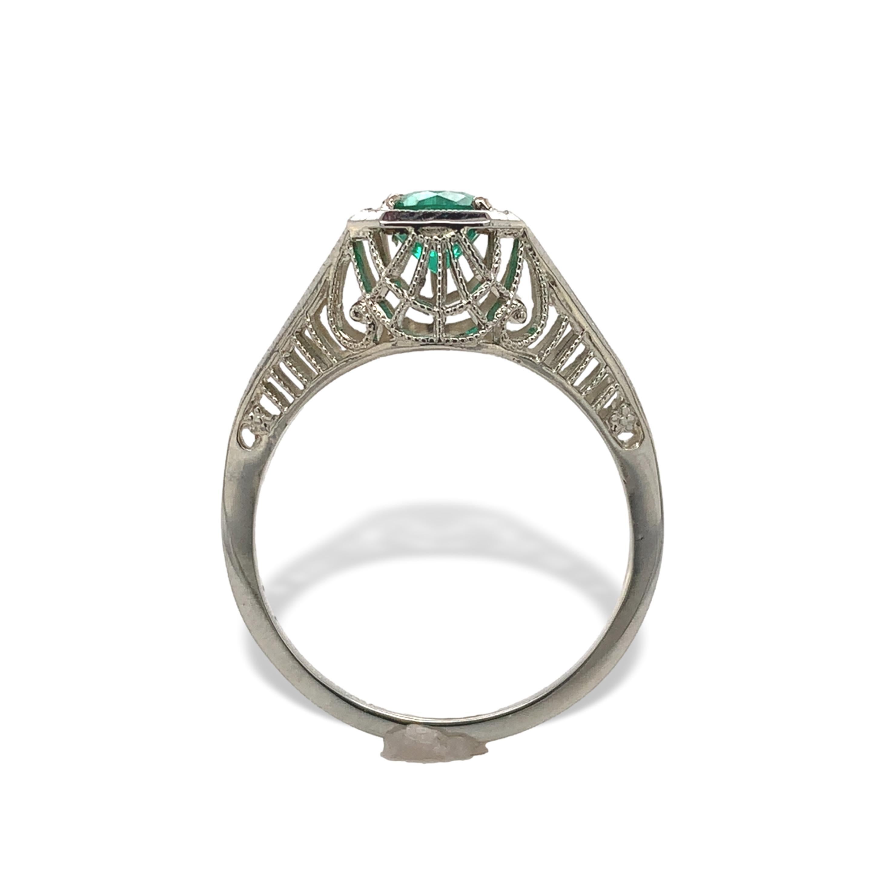 Bague filigrane Art déco en or blanc 18 carats, ornée d'une émeraude véritable. L'émeraude ronde mesure environ 4,5 mm et a une belle couleur vert gazon. Les côtés sont gravés à la main et le filigrane est très net et en très bon état. L'émeraude