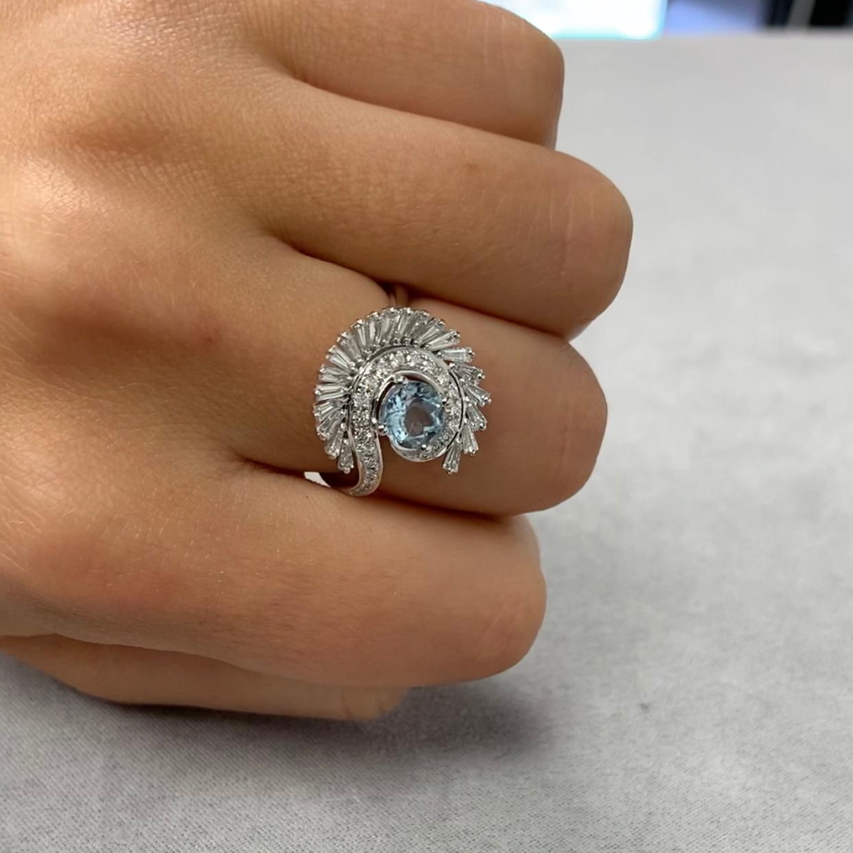 18K White Gold Ring Featuring Round Aquamarine, and Spiral Halo of Round and Baguette Diamonds. Finger size 6.5, adjustable upon request/quote. Aquamarine evokes the purity of crystalline waters, and the exhilaration and relaxation of the sea. Item