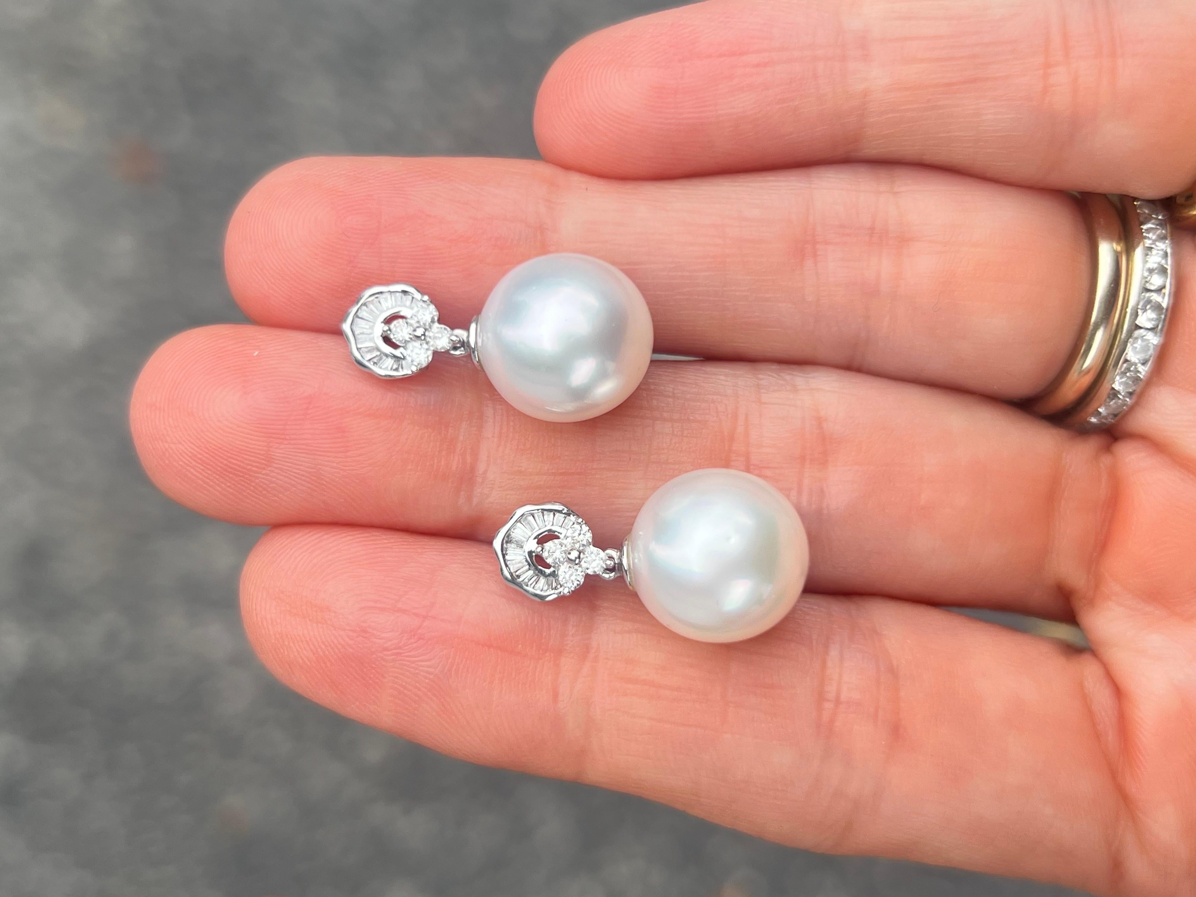 Add a feminine finishing touch to your ensemble with this beautiful diamond and pearl drop earring. Made in a contemporary style, baguette and round diamonds create an architectural element that resemble new deco designs. Below it dangles a lustrous
