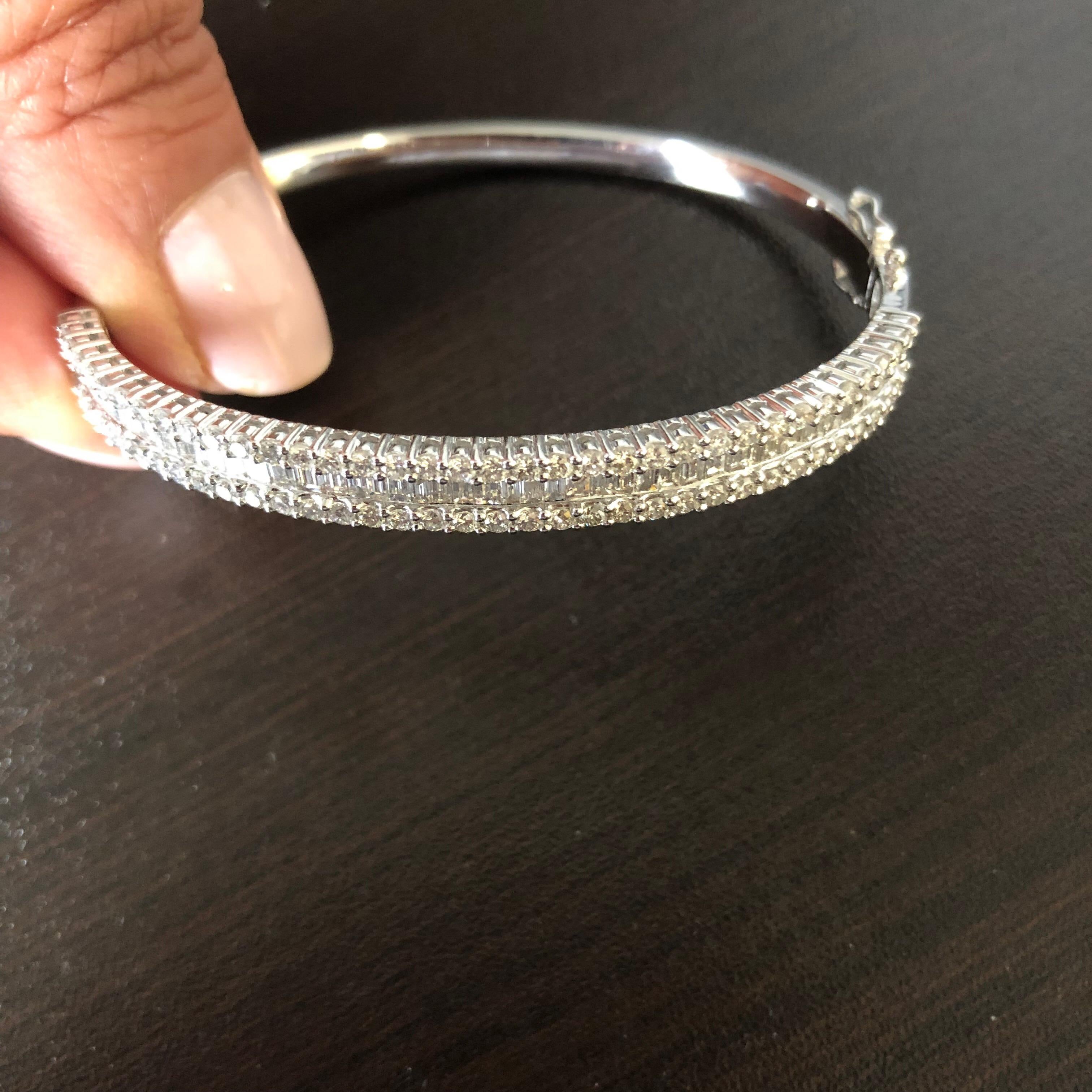 This beautiful diamond bangle is set in 18K white gold. The bangle consists of 2 rows of round diamonds and one row of baguette diamonds. The total carat weight is 3.33. The color of the stones is F, the clarity is VS1-VS2.