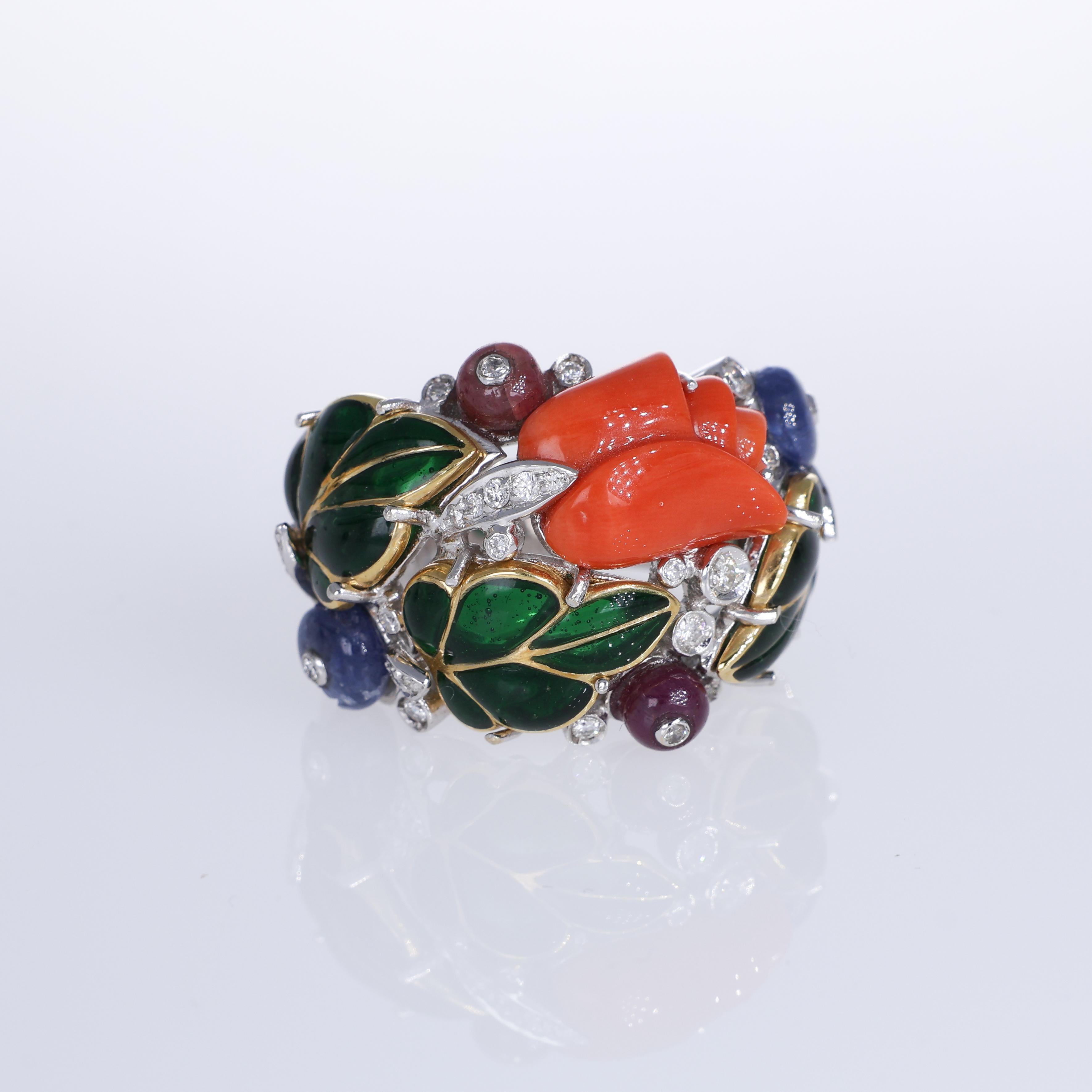 A masterpiece of craftsmanship, this 18K white gold band ring showcases a stunning coral flower intricately carved as the centerpiece. The design is enriched with cabochon-cut sapphires, rubies, and emeralds, harmoniously set among brilliant-cut