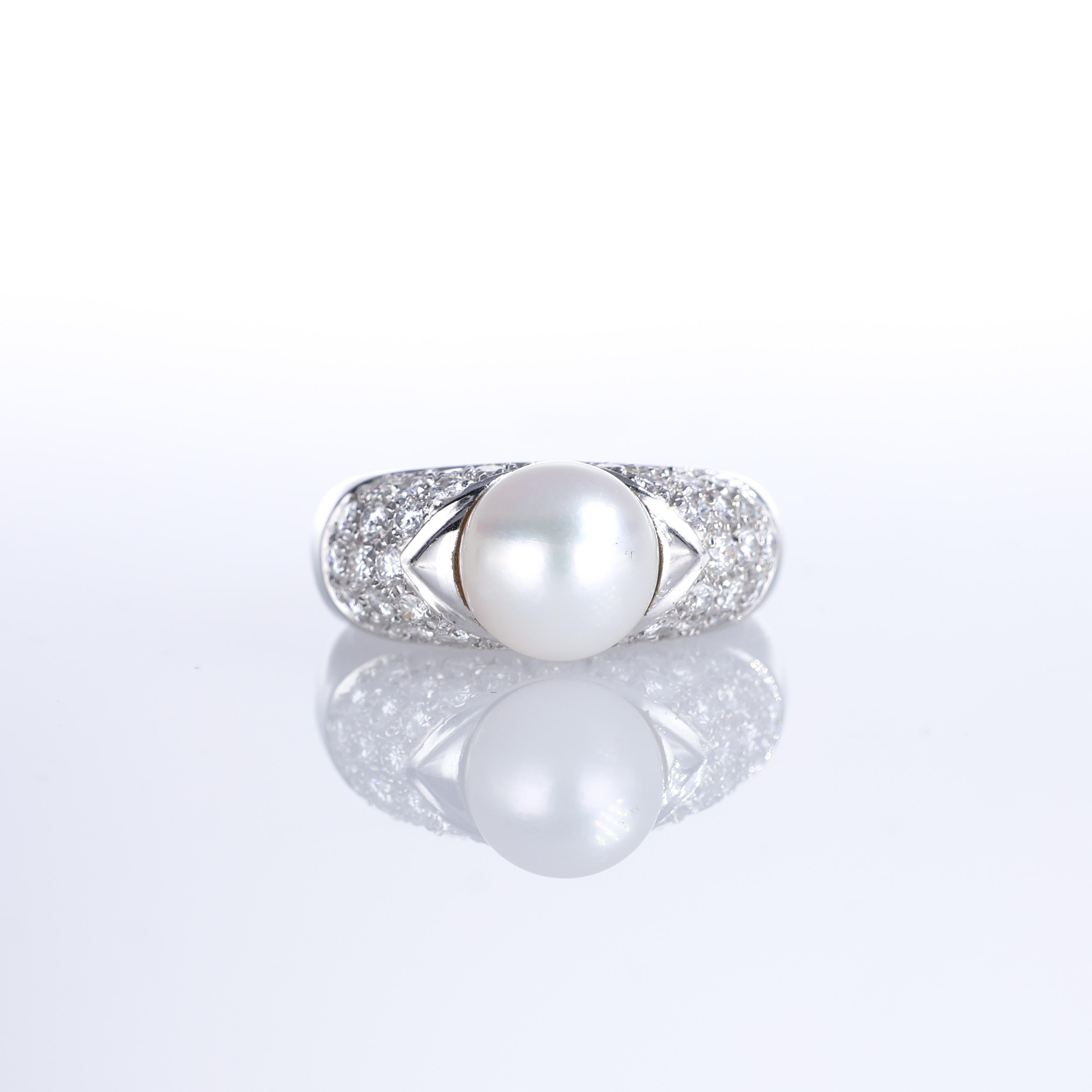 A refined 18K white gold band ring featuring a lustrous central pearl framed by two polished gold accents. The tapered design is enriched with pavé-set brilliant-cut diamonds totaling 0.95 carats, lending an understated elegance to the composition.