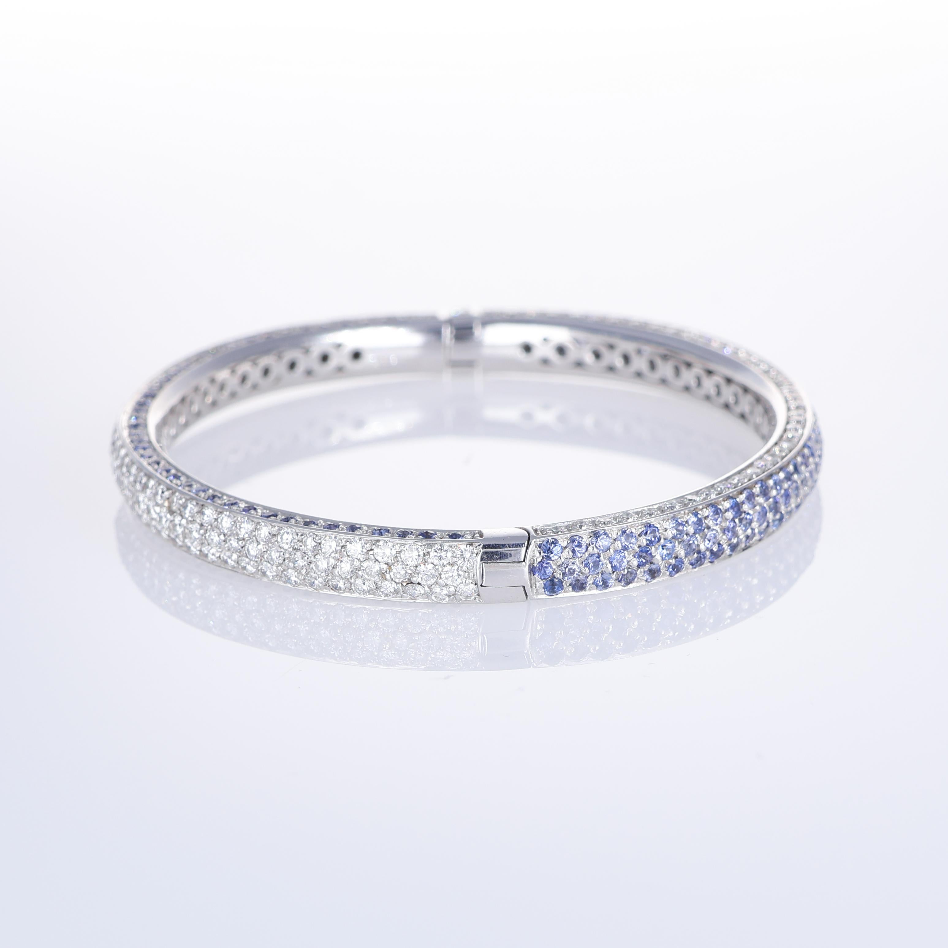 An exquisite 18K white gold bangle bracelet, fully adorned with a pavé of brilliant-cut white diamonds totaling 2.25 carats and deep blue sapphires totaling 6.55 carats. The seamless setting enhances the radiance of each gemstone, creating a refined