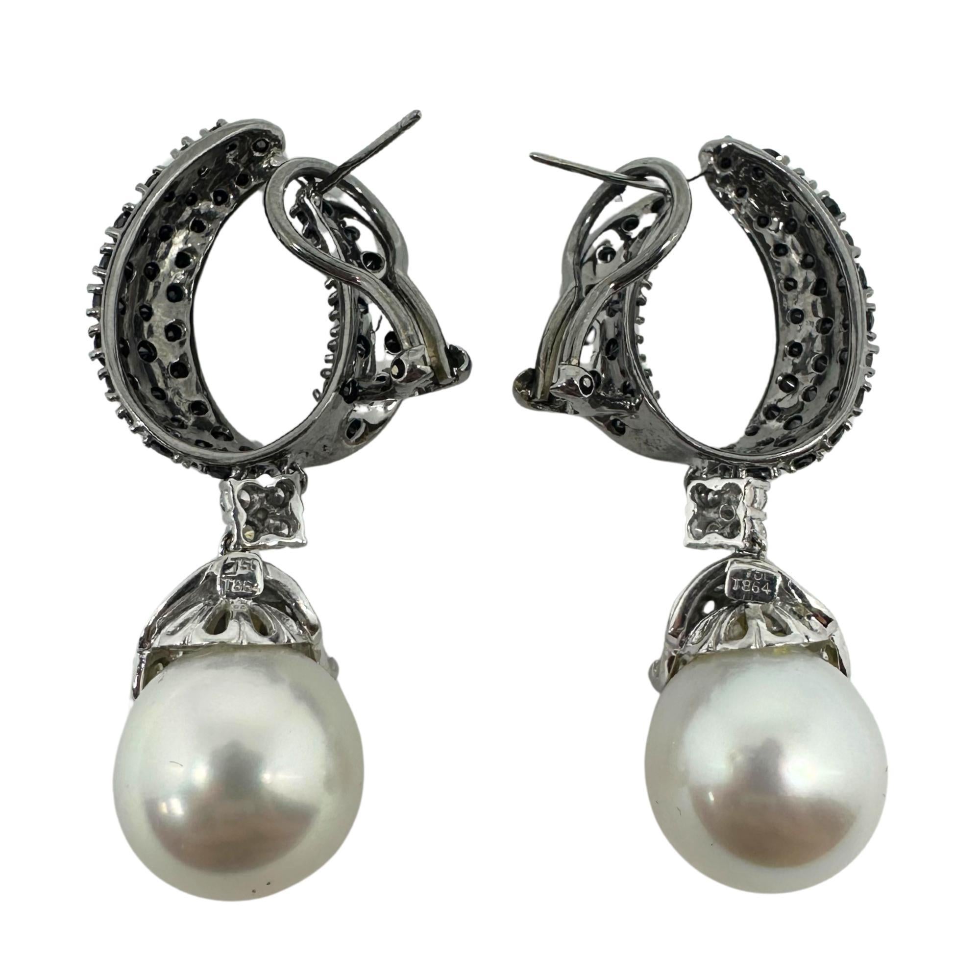 Questi orecchini presentano un design curvo a mezzo cerchio con diamanti neri incastonati. Da ogni cerchio è sospesa un'unica grande perla bianca, sormontata da foglie incastonate di diamanti che aggiungono morbidezza ed eleganza. La combinazione