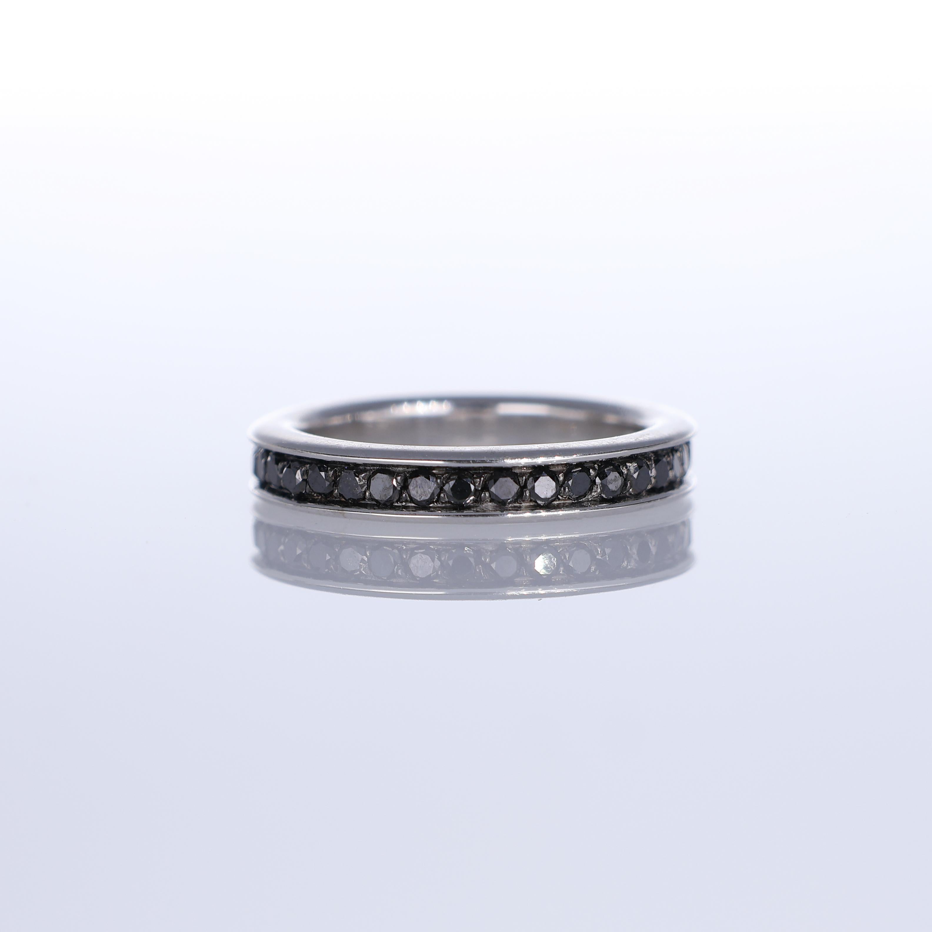 A sleek and modern band ring crafted in 18K white gold, featuring a channel setting of black diamonds for a bold yet refined aesthetic. The clean lines and continuous row of diamonds create a seamless, sophisticated look, making it an ideal piece