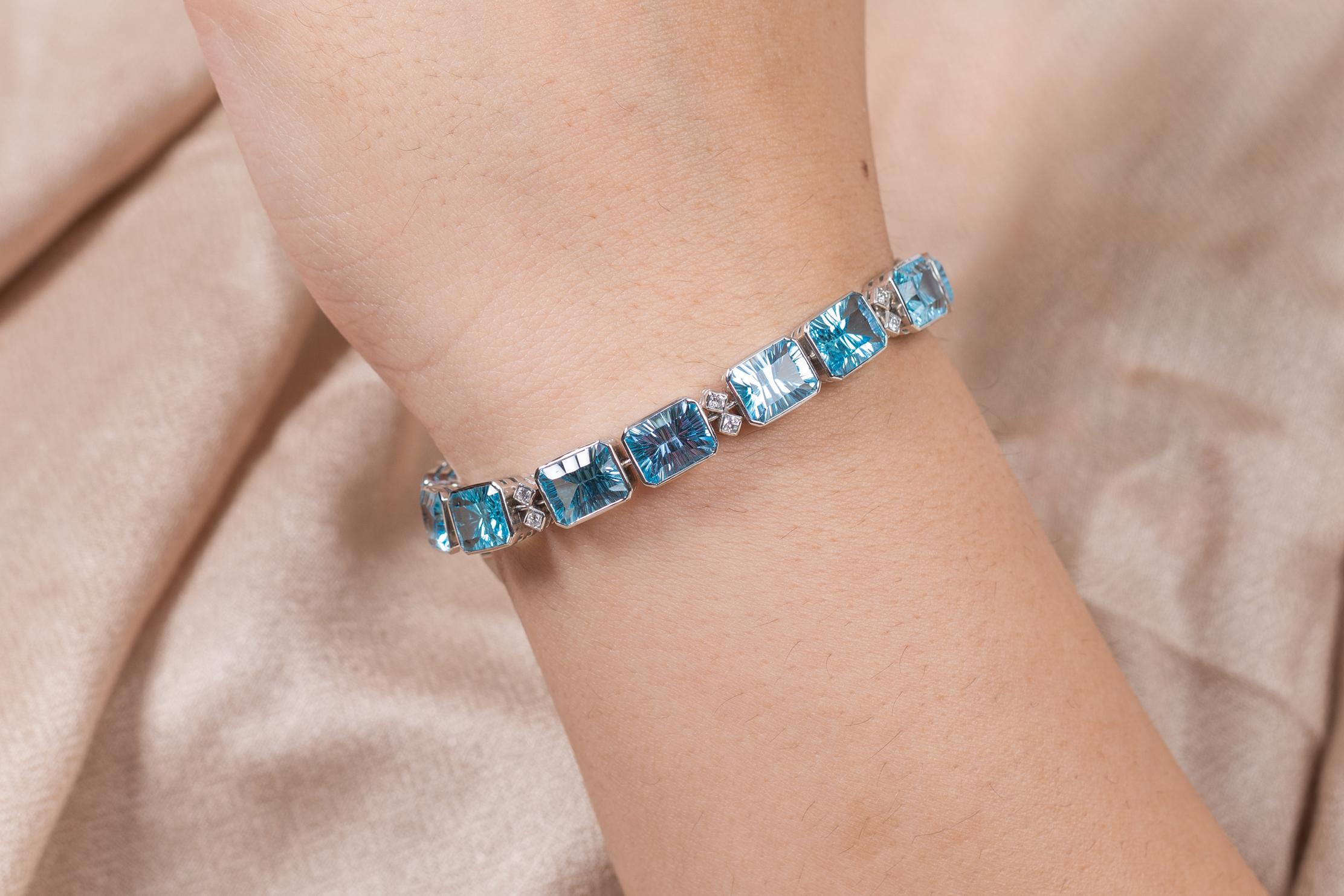 Ce bracelet de tennis en or 18 carats, composé de topazes bleues finement taillées et de diamants, met en valeur 16 topazes bleues naturelles étincelantes à l'infini, d'un poids de 40 carats. Il mesure 7.5 pouces de long. 
La topaze bleue aide à