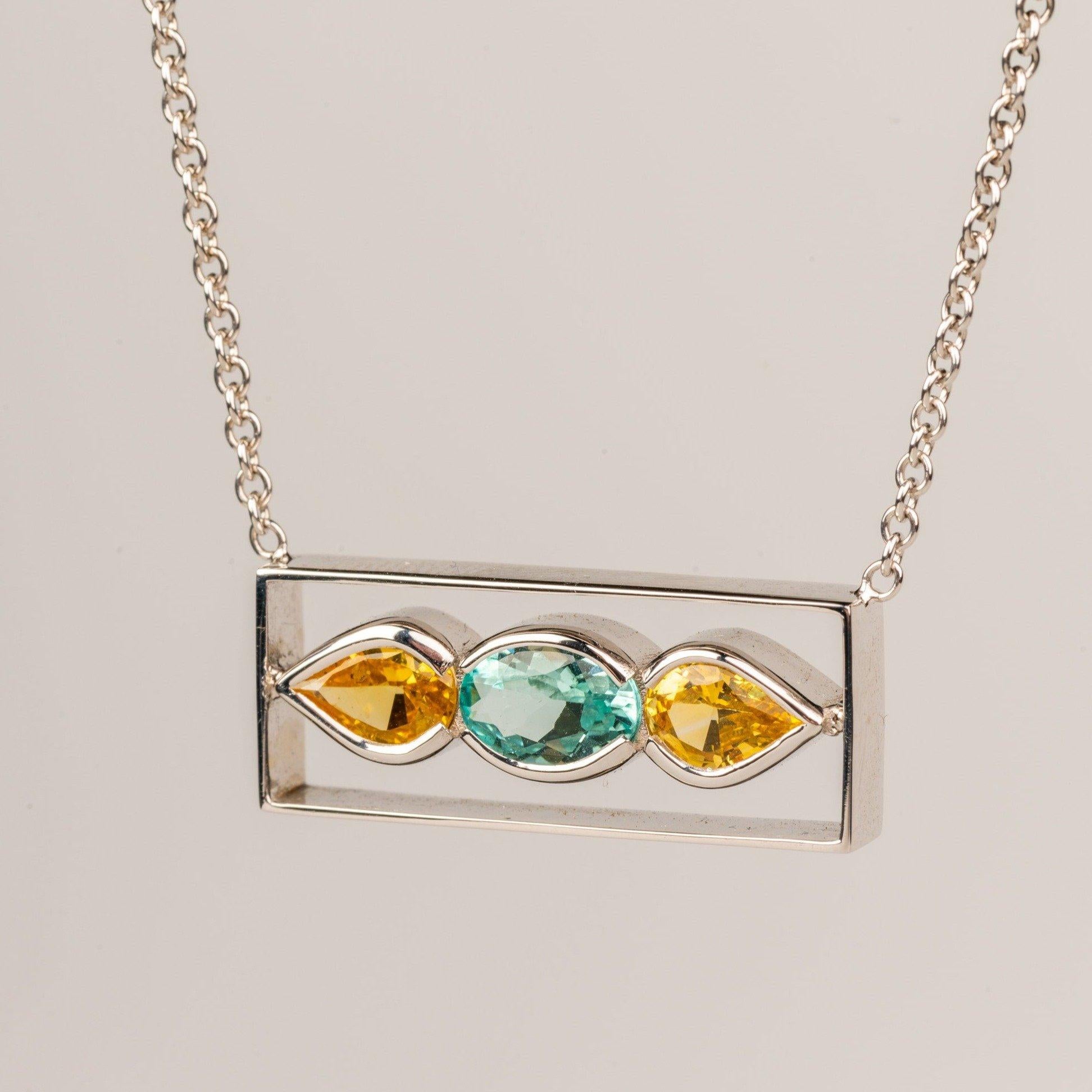 An 18k white gold bar necklace featuring one bezel set oval faceted blue tourmaline .66 carats and two pear shaped faceted yellow sapphires 1.12 carats, on a 16 inch white gold cable chain. This necklace was made and designed by Sydney Strong.